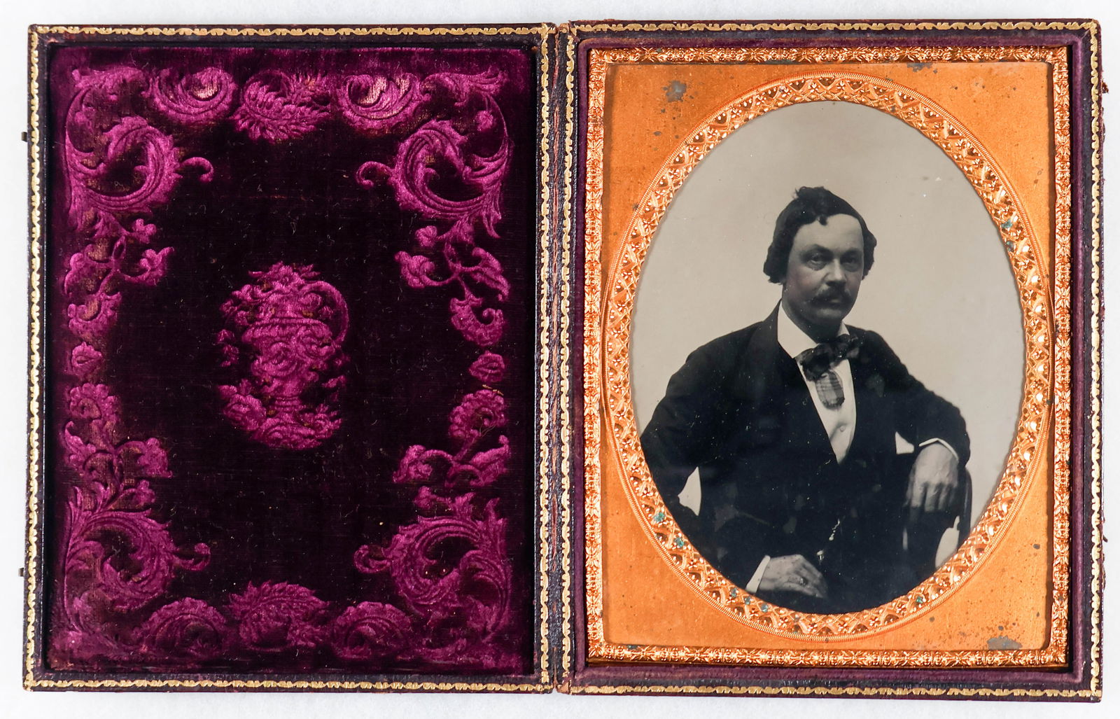 HALF PLATE AMBROTYPE: Excellent half plate ambrotype photograph, a portrait of a man in a suit, fitted in a unique cardboard case featuring intricate floral designs and with gold painted edges. Very good condition.