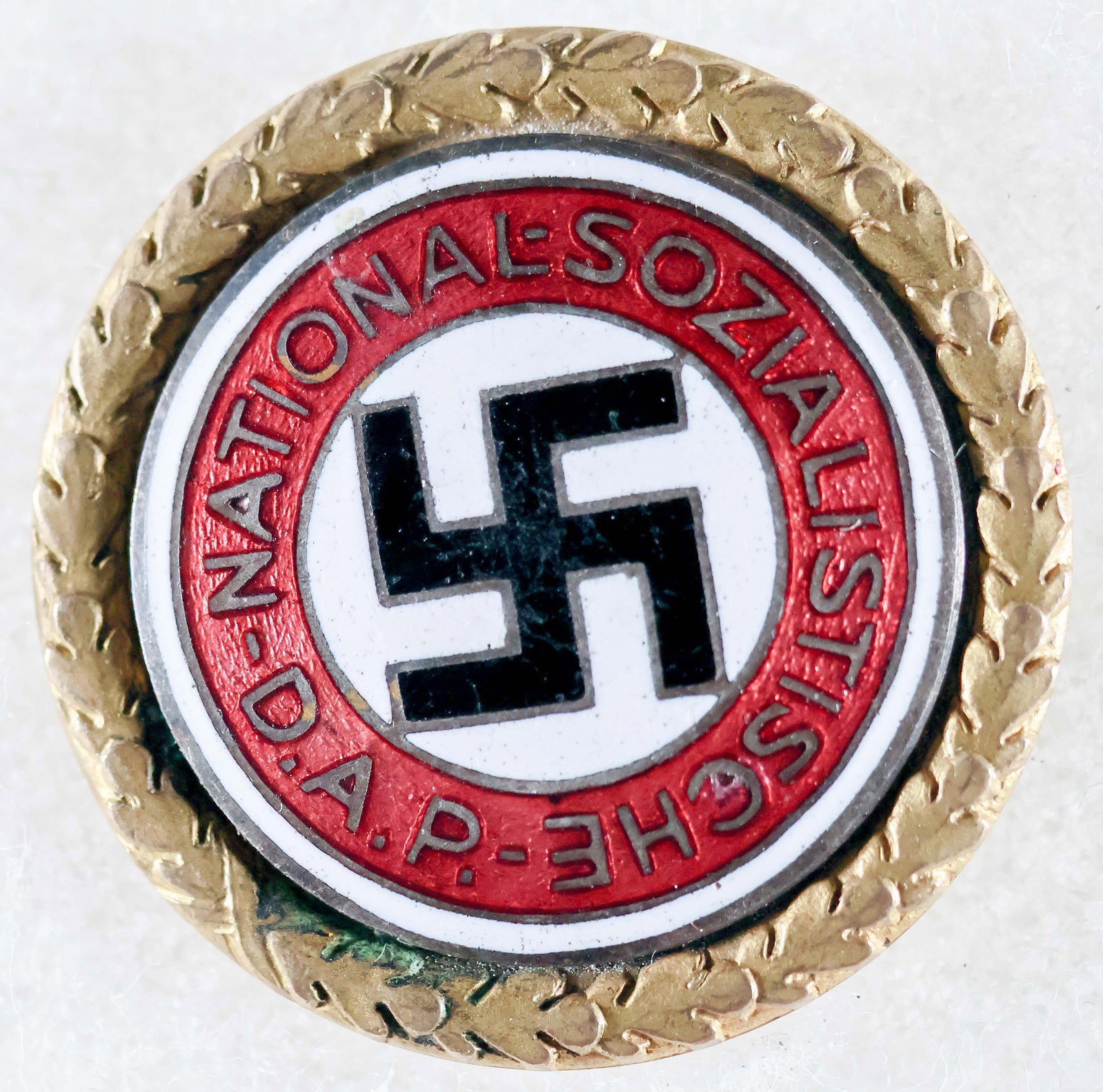 EARLY NSDAP GOLDEN PARTY BADGE: A fine example of a large-size, 30.5 mm, NSDAP Golden Party Badge, two-piece construction featuring the original party pin design in colored enamels, inset and attached to a brass laurel leaf patterne