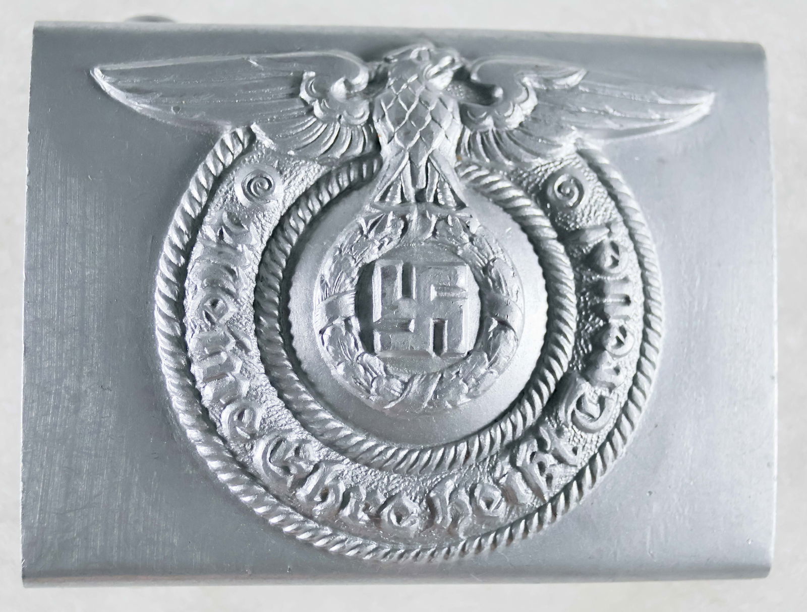SS BELT BUCKLE BY OVERHOFF: Excessively rare and likely unissued mint condition Waffen-SS belt buckle marked 'RZM 36/40 SS', indicating production by Overhoff & Cie in 1940. Constructed of aluminum with a silver paint finish, th