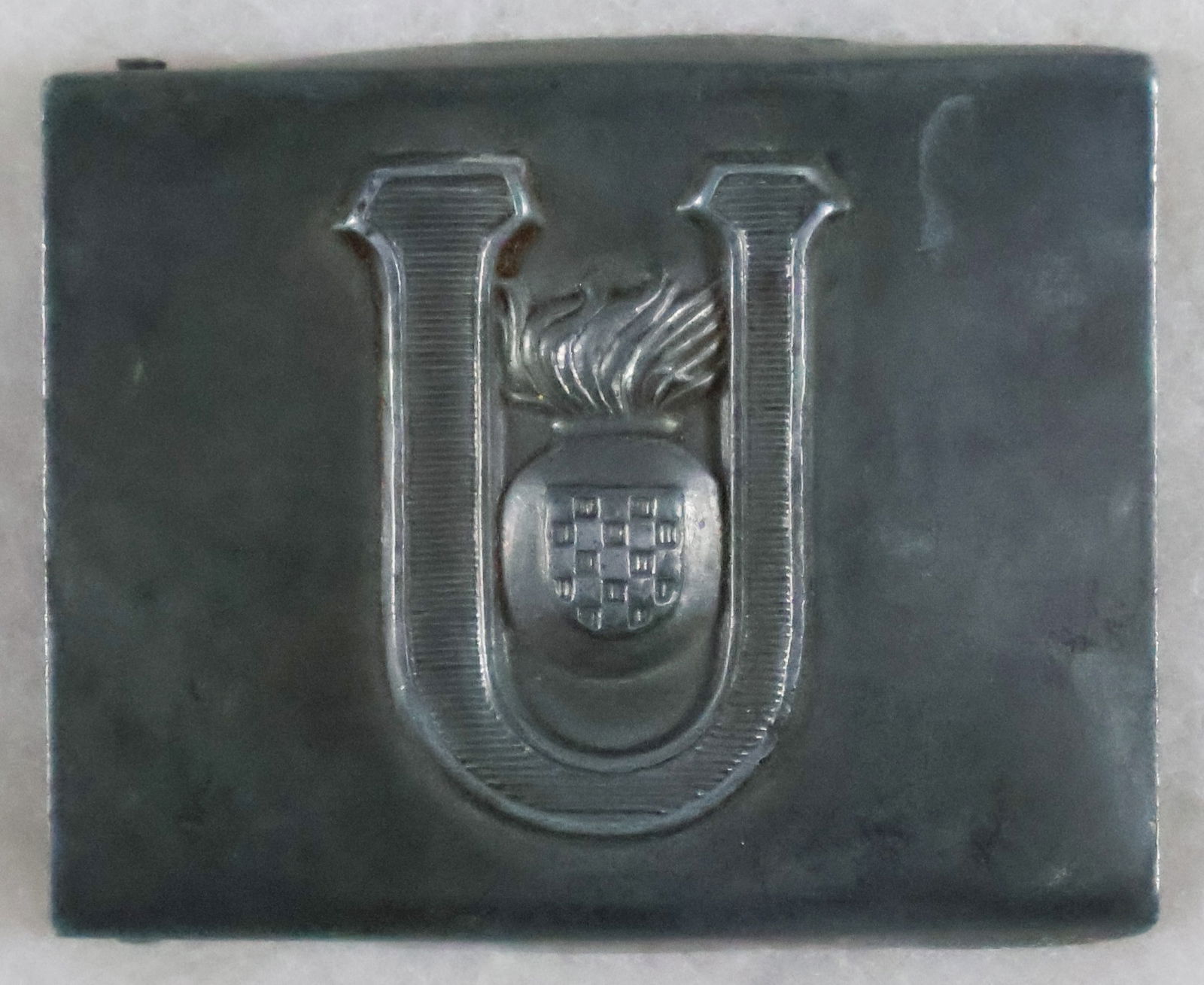 (CROATIA) USTASE EM/NCO BELT BUCKLE: Ustase EM/NCO’s belt buckle, patinated zinc construction, the obverse bearing a central raised Ustase insignia, the reverse affixed with a clip and attachment claws emanating from a functional r