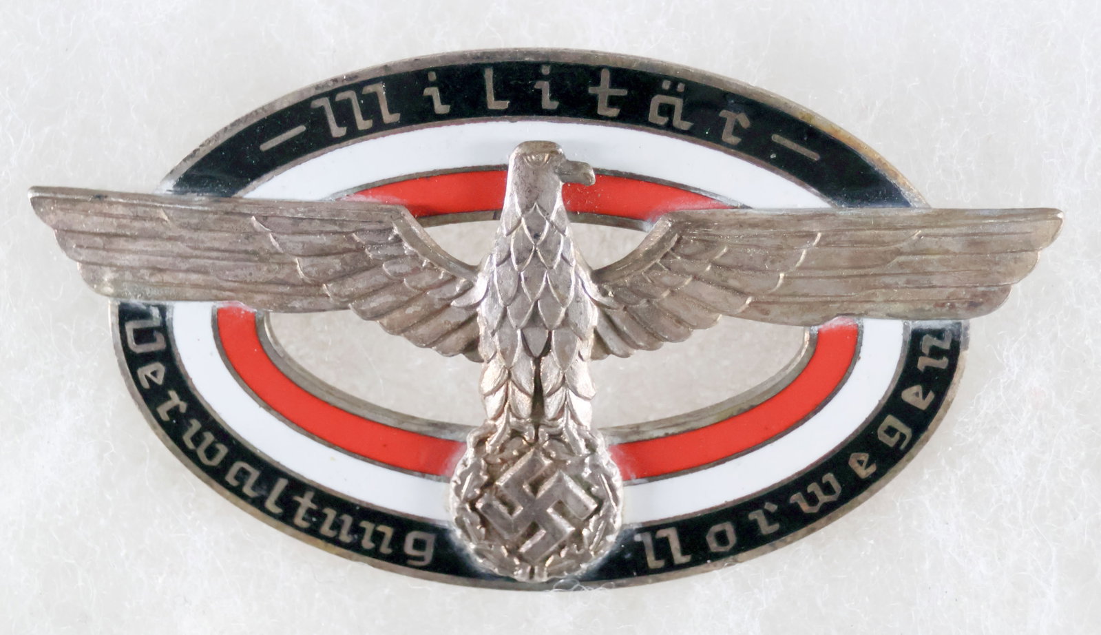 NORWAY MILITARY ADMINISTRATION BADGE: An exceptionally rare Military Administration of Norway badge, 3 x 1.5 in., showing a national eagle with wings spread clutching a wreathed swastika above an oval with the national colors of red, whit