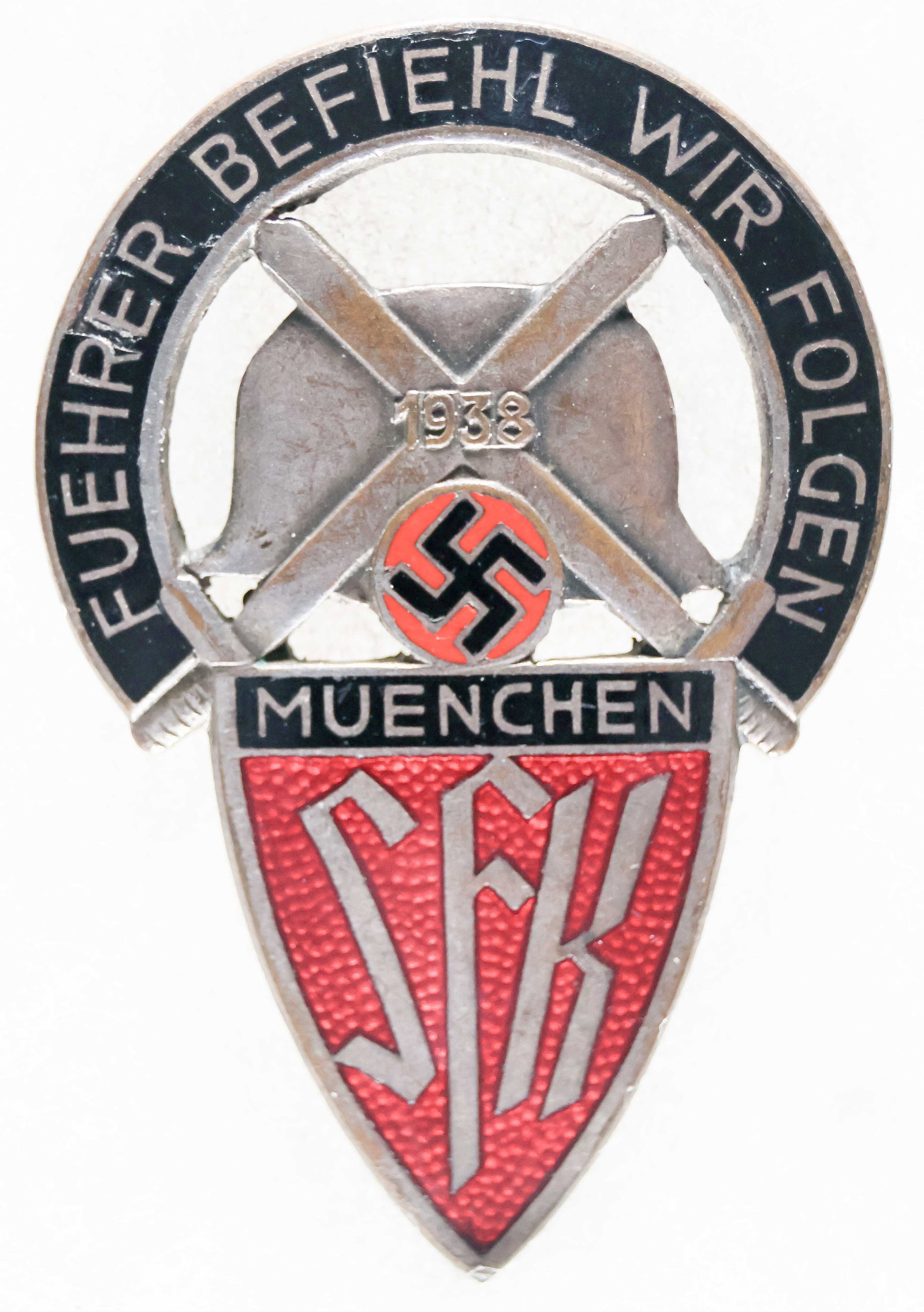 S.F.K. SUDETENDEUTSCHE FREIKORPS BADGE: Rare Nazi SFK Sudetendeutsches Freikorps enameled badge, 2 3/8 in. long, reads at top: 'FUHRER COMMANDS WE FOLLOW' and from the Munich section of the organization, dated 1938 with a stahlhelm, crossed