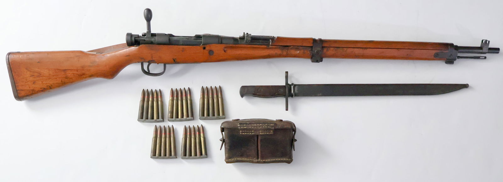CAPTURED JAPANESE ARISAKA TYPE 99 RIFLE, BAYONET AND CARTRIDGE CARRIER: A captured Japanese Arisaka Type 99 chambered for 7.7 x 58mm, with a five round internal magazine. This battlefield pick up is the Type 99 'Short' rifle at 44 in. in overall length, it is a matching r