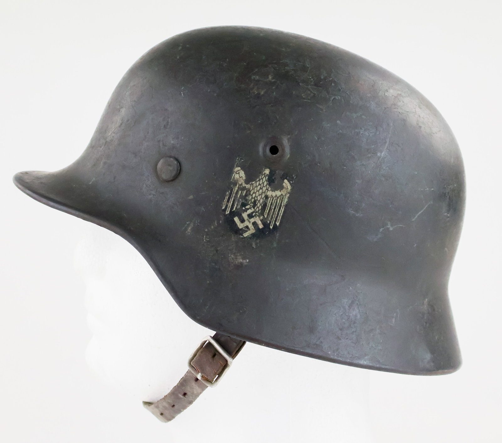 NAMED HEER M40 SINGLE DECAL HELMET: An intact M40 helmet in the original dark grey paint with a single decal of the national eagle clutching a swastika in its talons. Within is the original leather chinstrap, liner, and aluminum sweatba