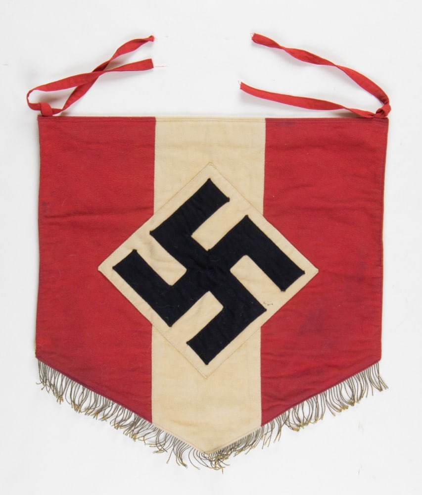 HITLER YOUTH DRUM BANNER: Cloth banner, 18 x 18 in., with a red field and singular vertical white stripe. At the center is a sewn-on white diamond bearing a separate black swastika. The bottom edge displays a 1 in. gold fringe