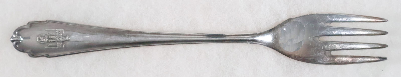 REICHS CHANCELLERY FORK: A silver-plated dessert fork once used in the Reichs Chancellery in Berlin, 7 in. long with a fluted design, the bottom bearing a left-facing eagle clutching a static swastika in high relief. This emb