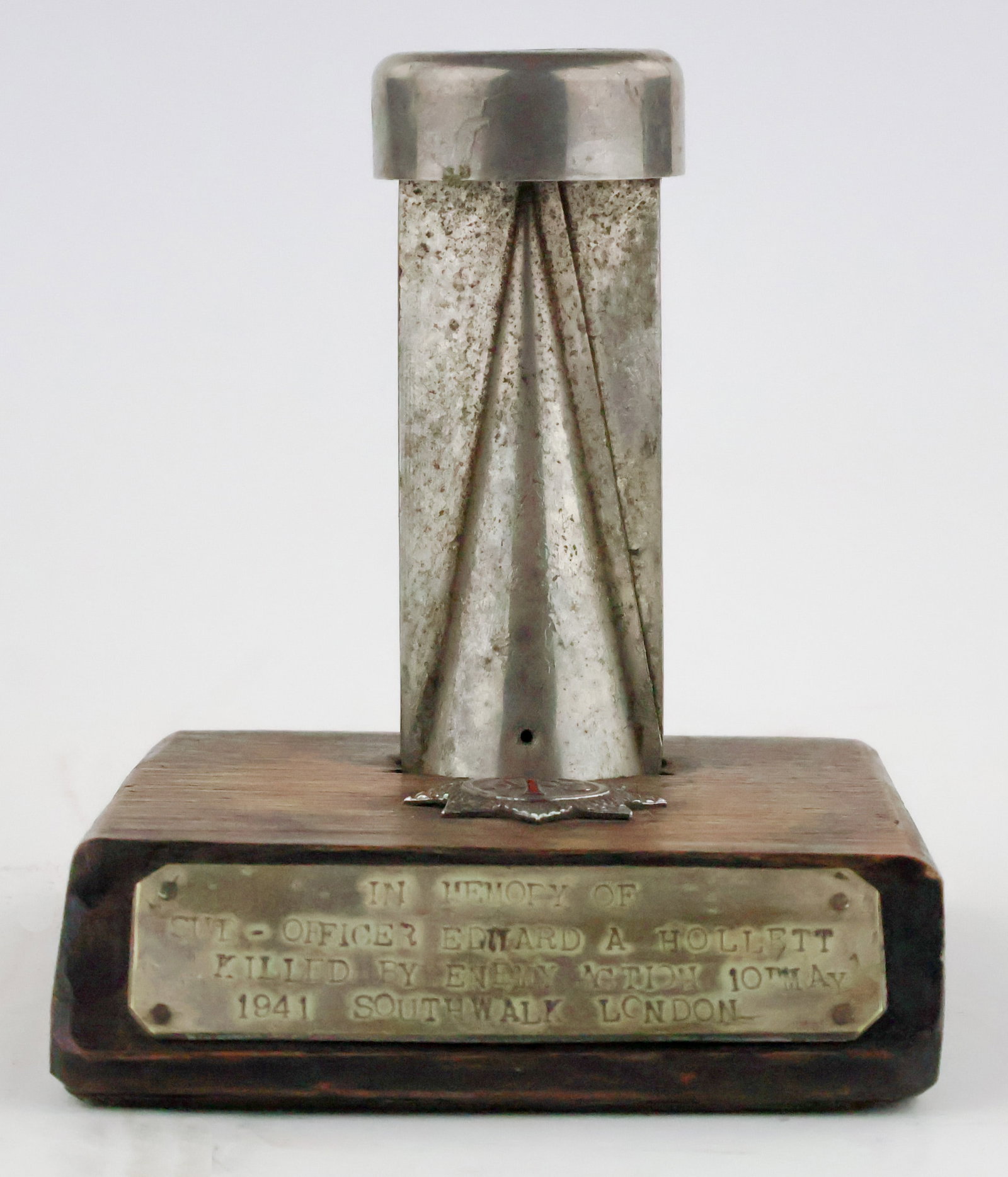 GERMAN INCENDIARY BOMB DISPLAY: A homemade display honoring a British A.F.S. (Auxiliary Fire Service) sub-officer killed in the line of duty. A 5 x 5.75 in. wood base supports the tail section of a German incendiary bomb, 4.5 in. lo