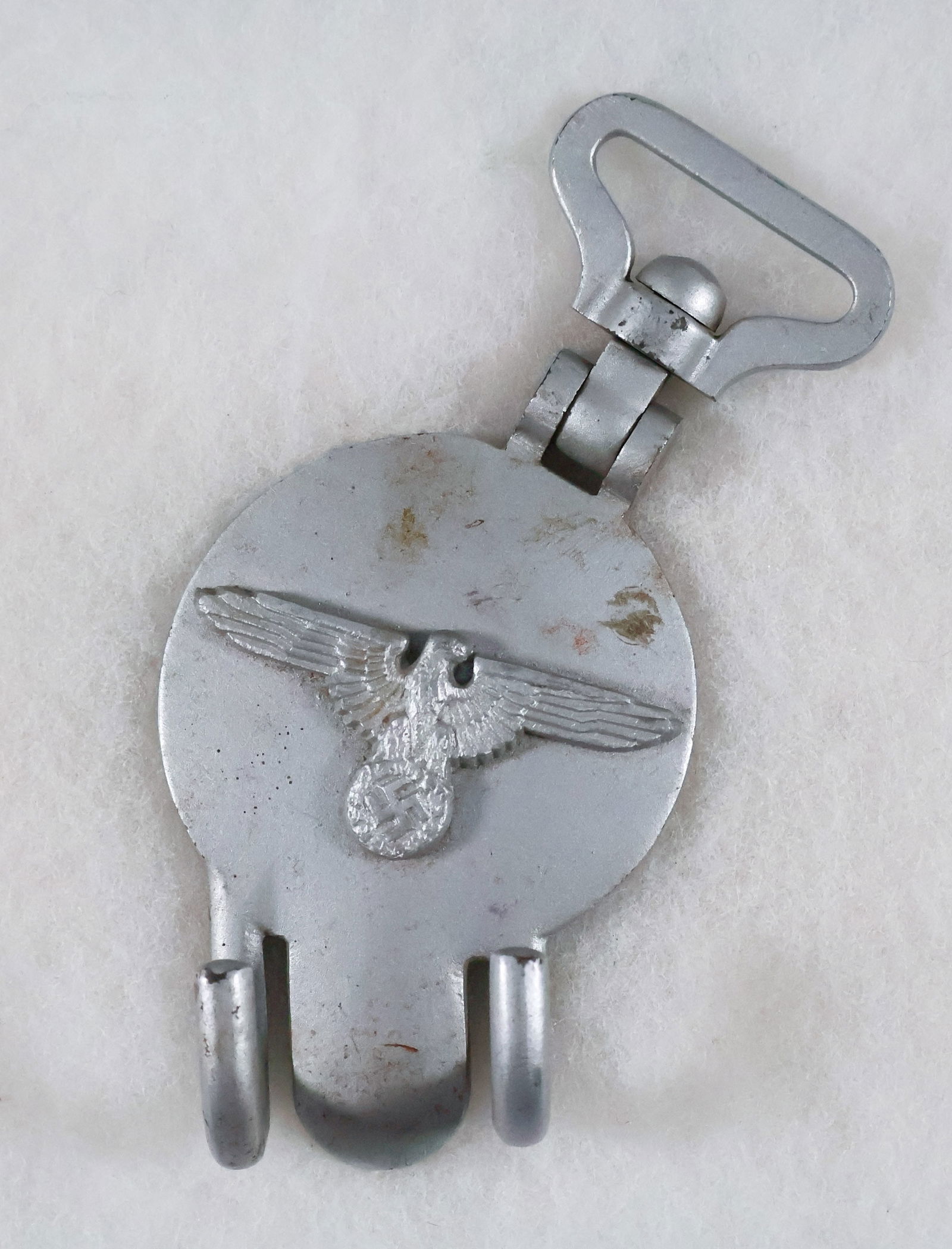 SS DRUM HANGER: Solidly constructed SS drum hanger, approx. 6 in. long overall, iron with silver paint finish, two hooks at bottom and a swivel at top. A national adler with mobile swastika is affixed at center. Mark