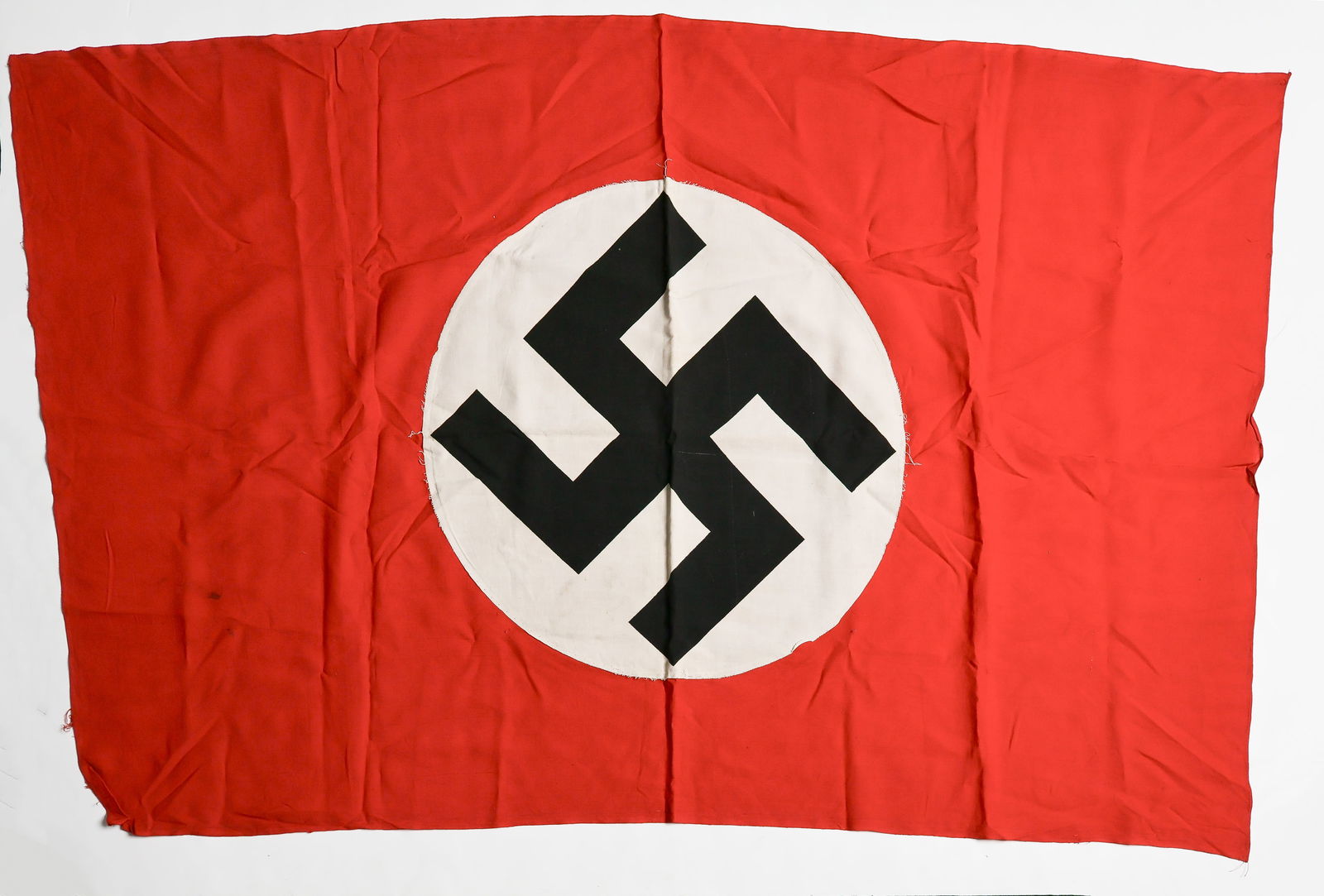 NSDAP FLAG: NSDAP flag, 46 x 30 in. two-sided cotton construction, separate roundels with printed swastika sewn to the red body of the flag. Hemmed at the left and right sides, woven edges at the top and bottom,
