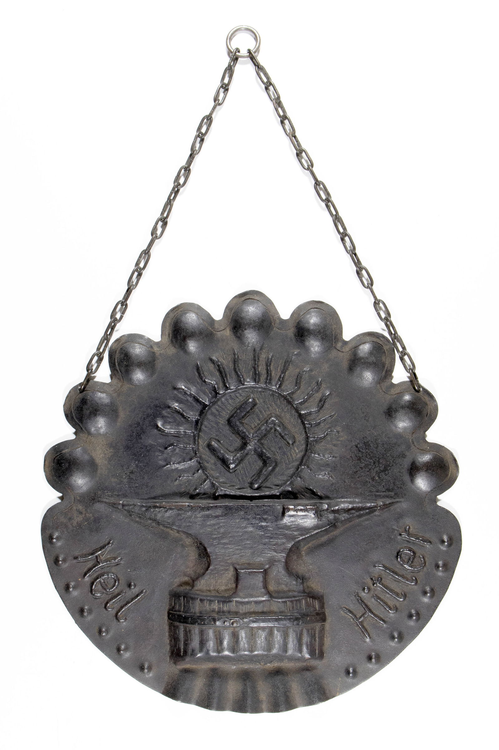 'HEIL HITLER' SUN AND ANVIL WALL PLAQUE: An early pro-Nazi hand-forged iron wall plaque, circular 12.5 in. diameter, bearing early Nazi symbolism including a swastika within a sun ('sonnenrad'), and an anvil, likely a reference to Thor's ham