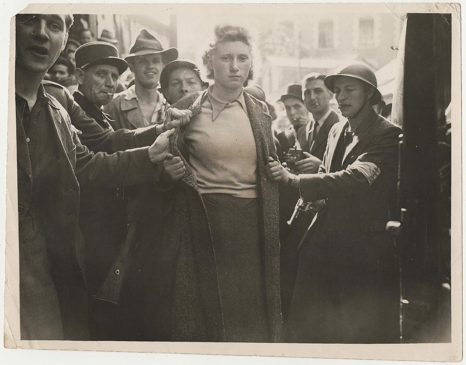 COLLABORATIONIST FRANCE: A pair of World War II date press photos, the first 9 x 7 in. b/w, Aug. 4, 1944, showing a French woman collaborator being rounded by French Forces of the Interior in the city of Rennes. The second,