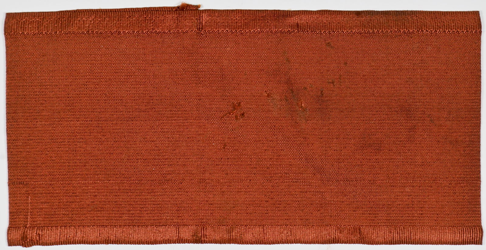 GREEK JEW'S IDENTIFYING ARMBAND: Excessively rare armband obliged to be worn by Jews in Greece during the German occupation of that country, 15.5 x 3.75 in. red rayon with distinctive upper and lower borders in a contrasting weave.