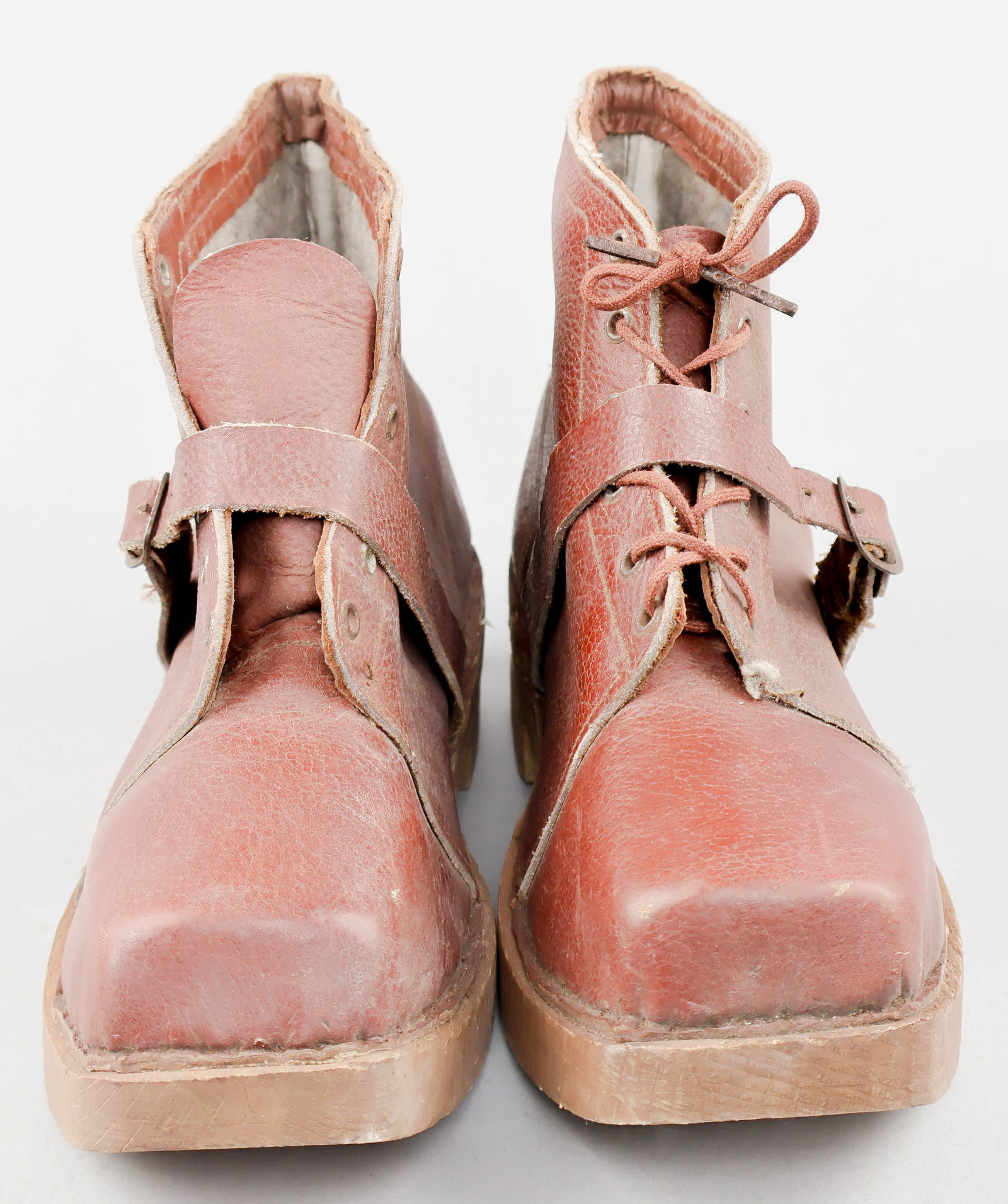 UNISSUED CONCENTRATION CAMP PRISONER’S SHOES: Pair of unissued shoes intended for the use of forced laborers at concentration and labor camps, or by prisoners of war. The shoes bear thick wood soles to which are nailed the reddish-brown leather