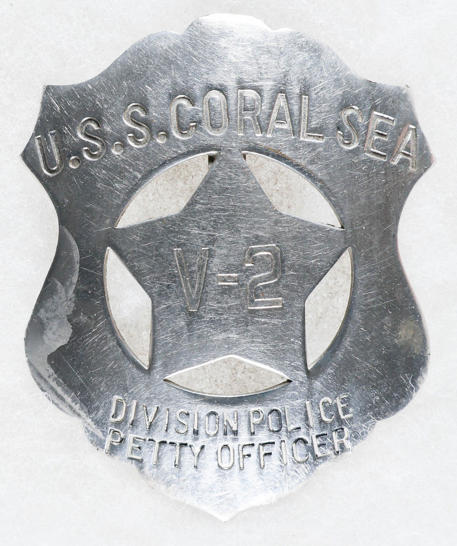 U.S.S. CORAL SEA POLICE PETTY OFFICER'S BADGE: Rare U.S. Navy badge from the USS CORAL SEA (CV/CVB/CVA-43), a Midway-class aircraft carrier. The simple steel badge is 2.75 in. tall, shield shaped with a star placed in the cut-out center. The