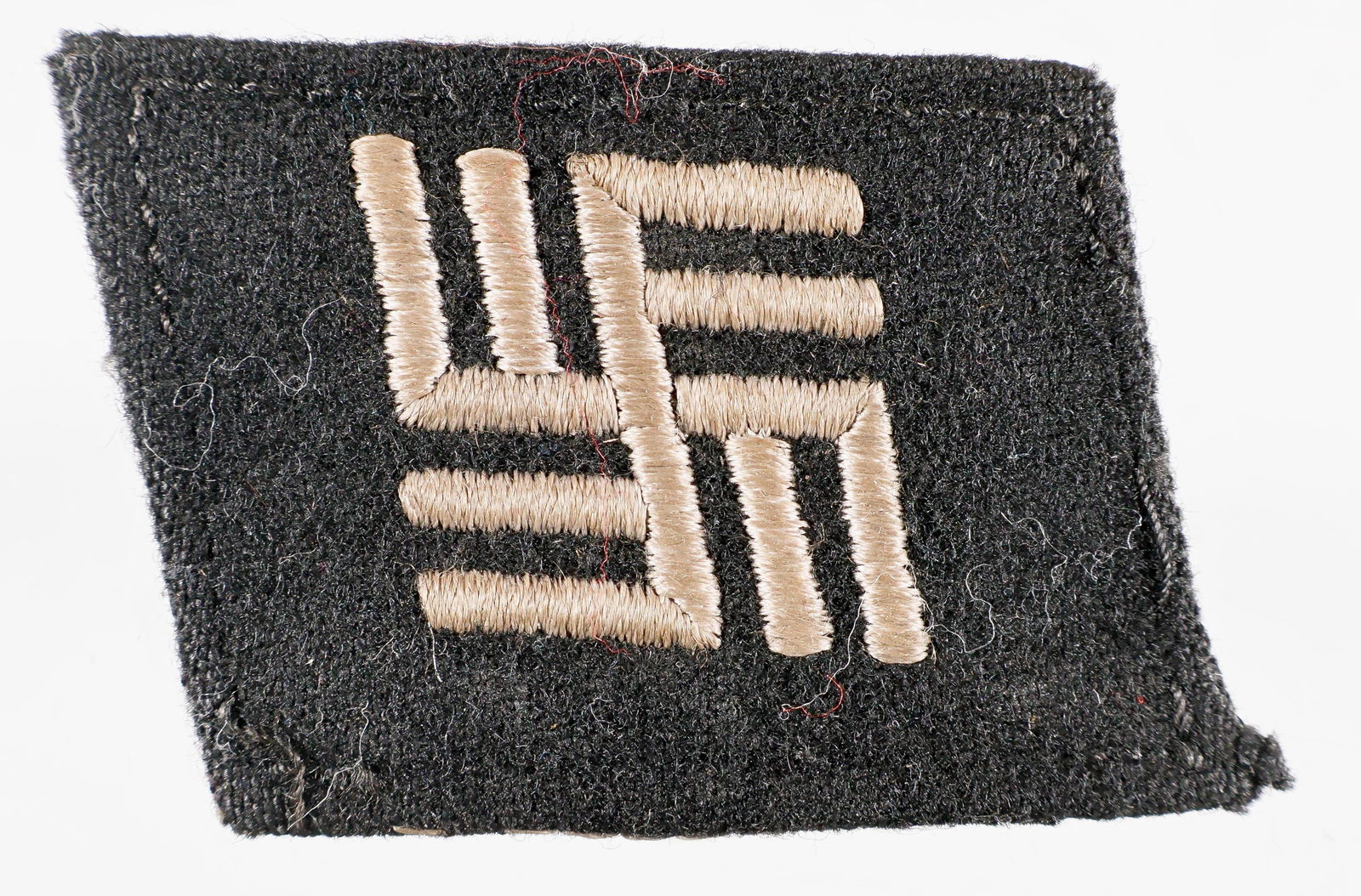 CONCENTRATION CAMP GUARD'S COLLAR TAB: Rare temporary concentration camp guard's collar tab, garment-removed with some threads still attached, 1 5/8 x 2 1/8 in. with white stitching attaching the embroidered black cloth to the buckram