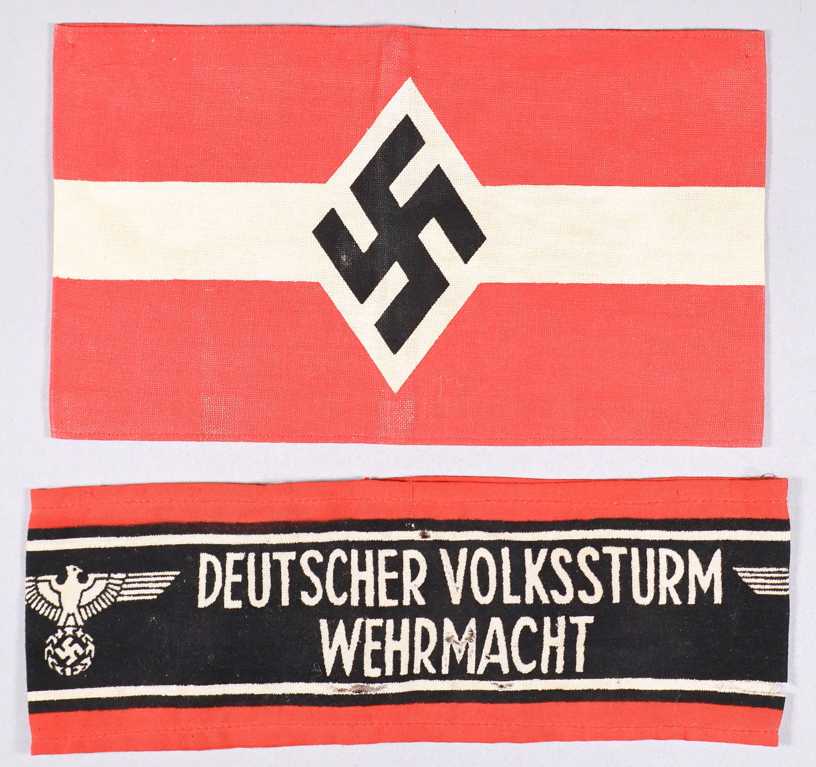 HITLER YOUTH AND VOLKSSTURM ARMBANDS (2): Pair of German armbands, includes: Hitler Youth armband, 14 x 4.25 in. printed cottonand joined at the ends, sold with a cotton armband, 15 x 2.5 in., joined at the ends, bearing the printed text: