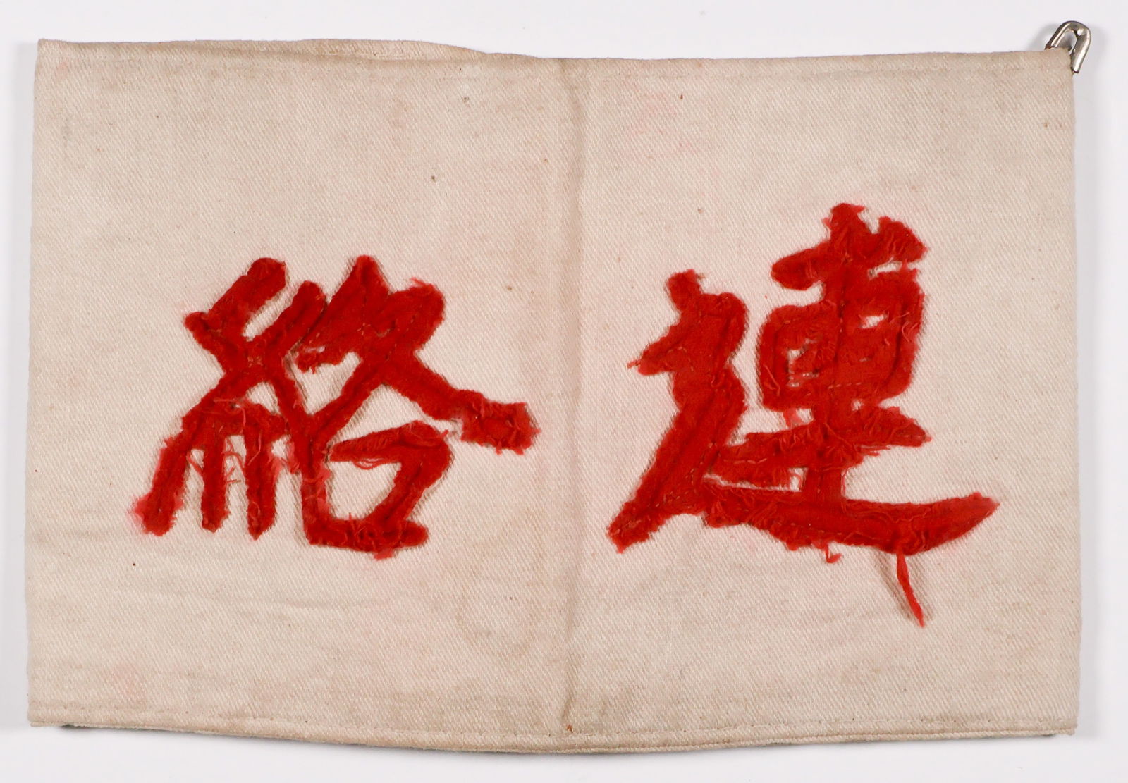 JAPANESE OFFICER'S ARMBAND: Japanese Liason Officer's Armband, 13.5 x 4.25 in. heavy white cloth with red kanji lettering sewn to the backing, grommets on reverse with original ties. The grommets are a bit rusted and the band