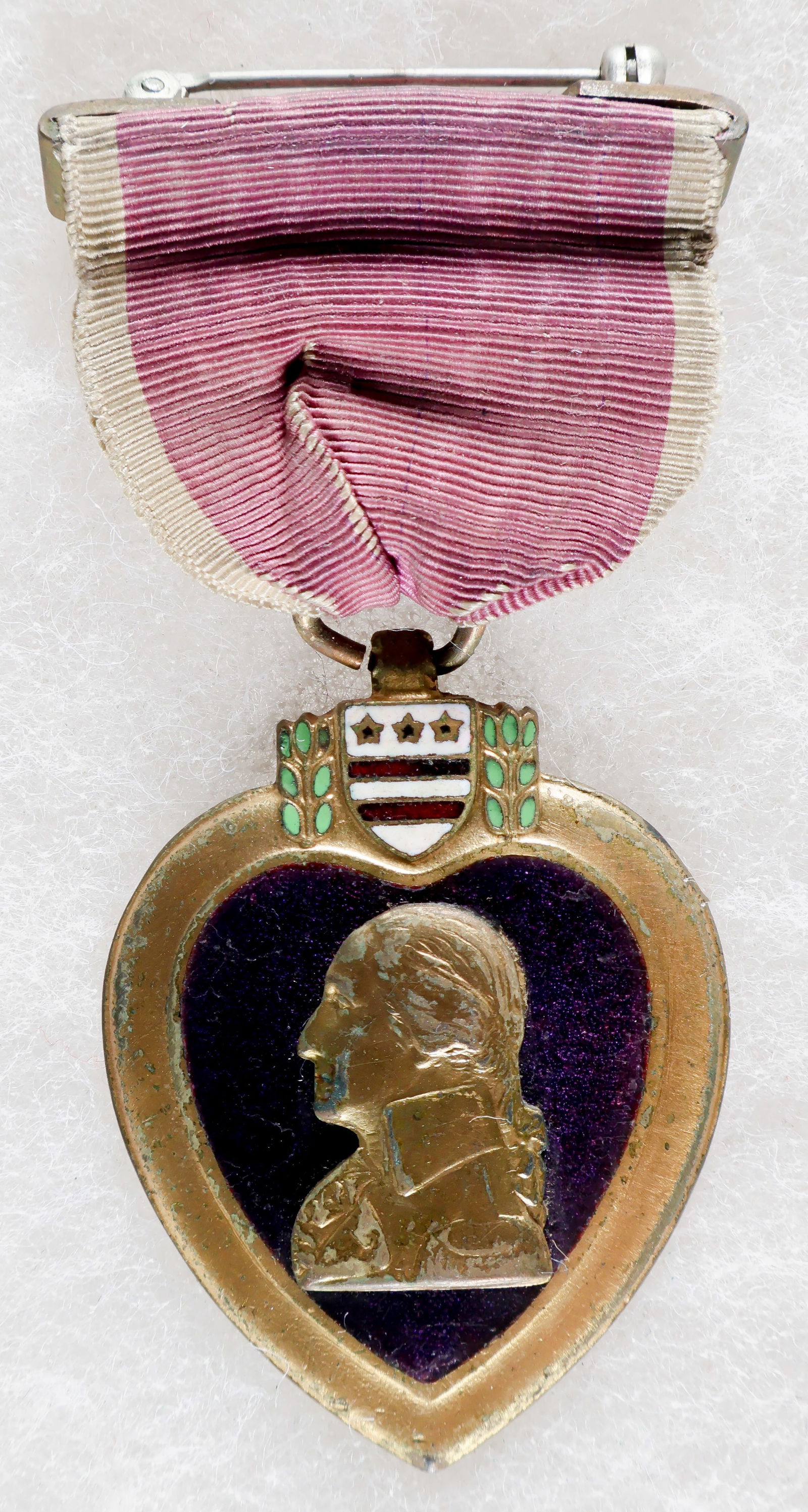 NAMED AND CASED PURPLE HEART MEDAL: A Purple Heart medal with early crimped pinback suspension, engraved on the reverse as being awarded to a Eugene Hairston. The medal is housed in its original presentation case, and shows some fading