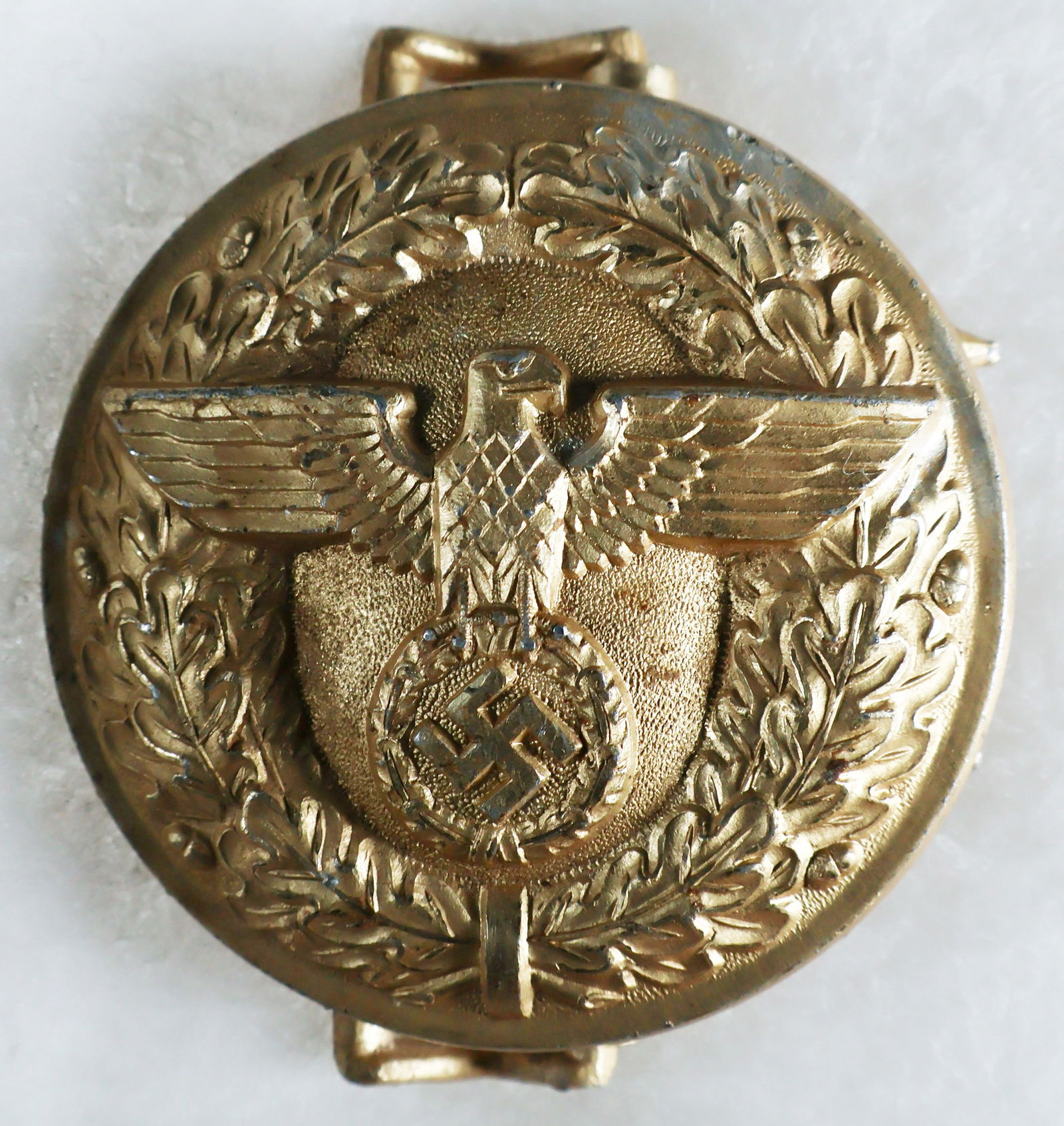 NSDAP POLITICAL LEADER'S BELT BUCKLE: NSDAP Political Leader's belt buckle, solid aluminum construction with gold wash, 2.25 in. wide, the reverse stamped by maker 'M4/24' for Friedrich Linden. A few tiny dings to the surface and some