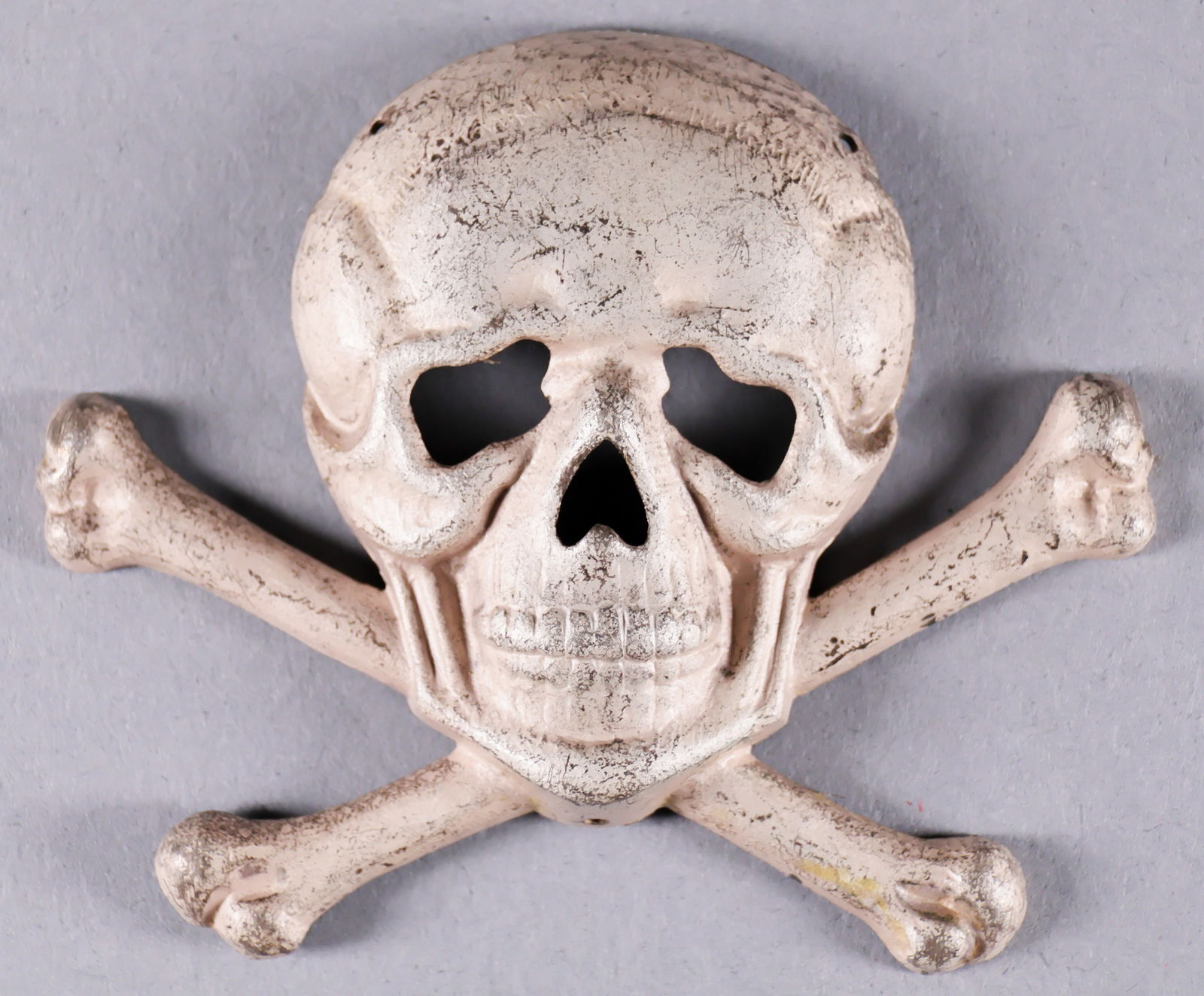 TOTENKOPF HAT INSIGNIA: Unusual Totenkopf hat insignia, 2.75 in. wide, stamped and silver washed, with three small holes for sewing to headgear. Exact use unknown, possibly a Freikorps issue. Very good.