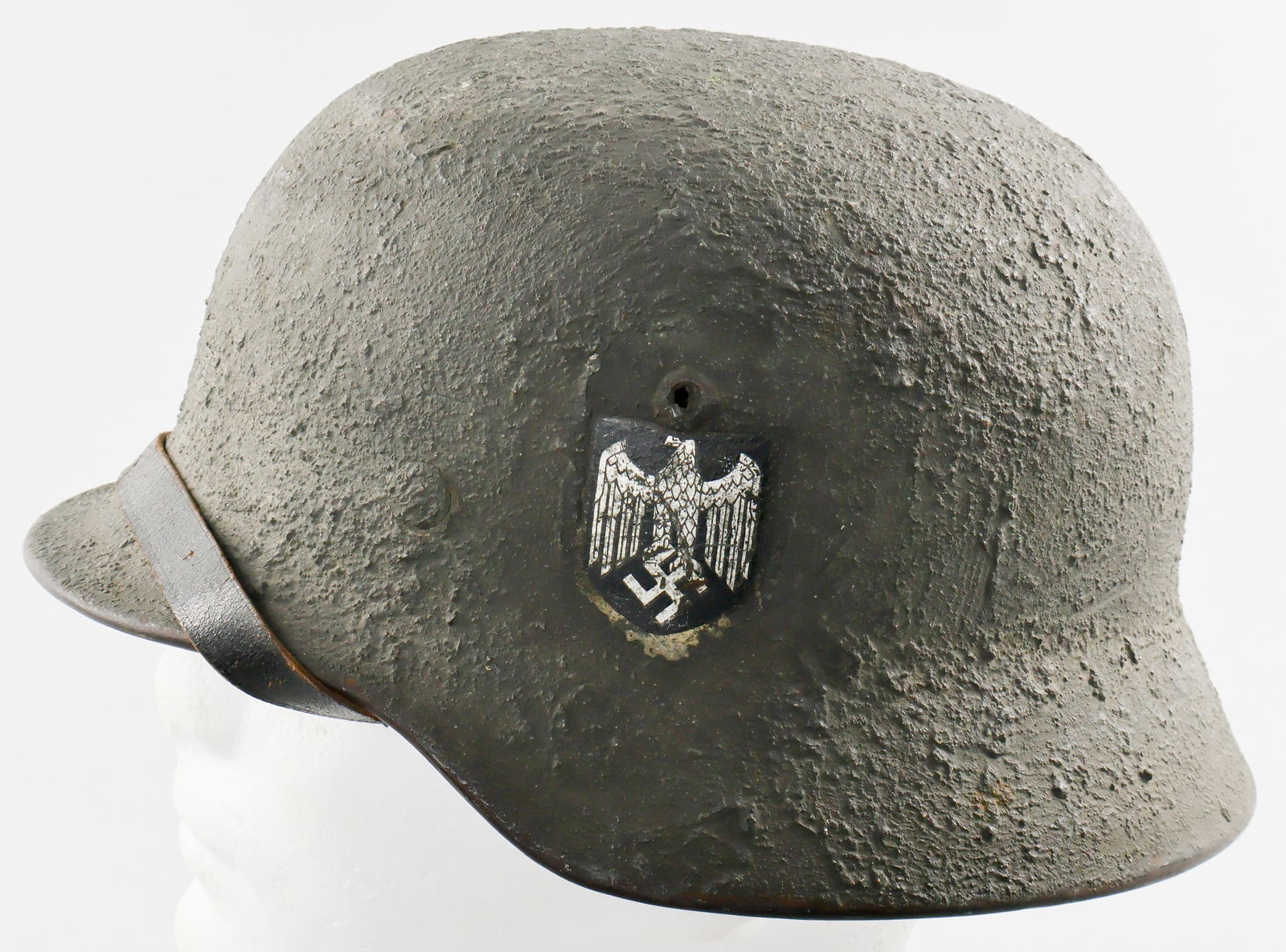 M35 HELMET WITH 'ZIMMERIT' CAMOUFLAGE: A true rarity, a German M35 single decal Heer helmet with hand-applied 'zimmerit' camouflage finish leaving no doubt that it saw combat use. The finish was neatly applied so as not to obscure the Wehr