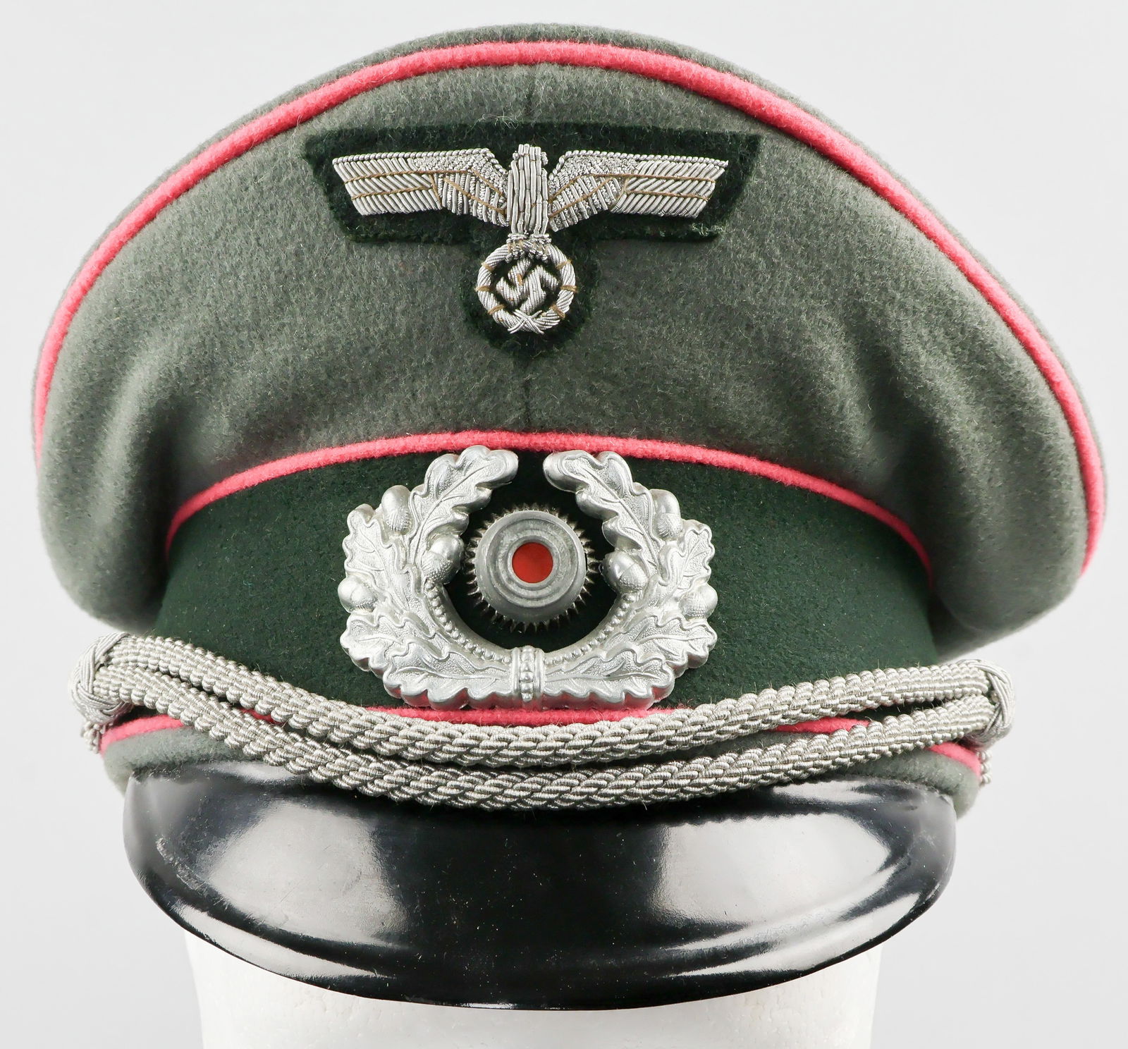 PANZER OFFICER'S VISOR CAP: Superb example of a Panzer officer's visor cap. The cap bears a field gray wool body with pink piping at top and on either side of the black side band as well. A silver bullion eagle with dark green