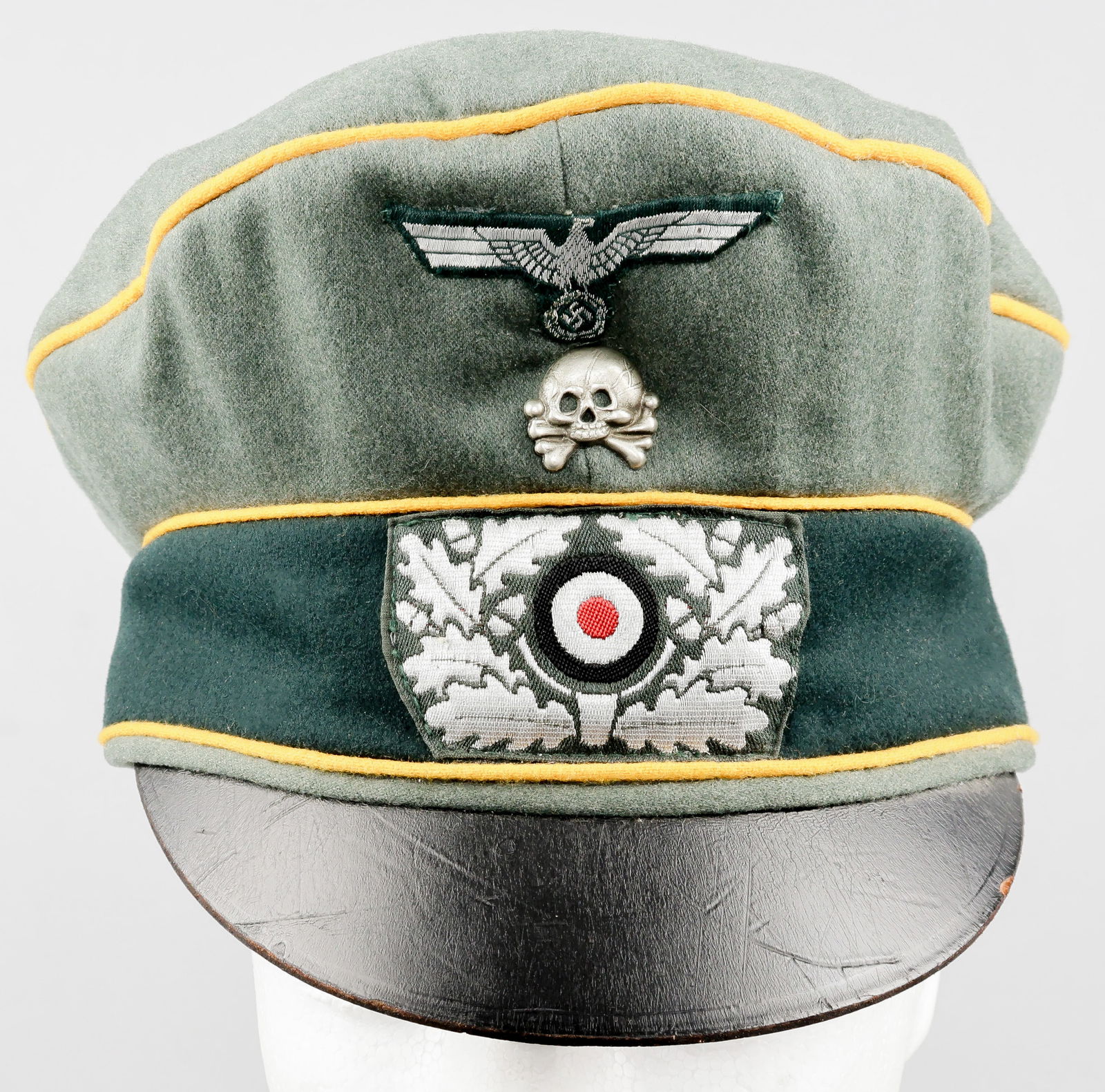 HEER CAVALRY OFFICER’S CAP WITH ‘LEIBHUSAREN’ TRADITIONS SKULL: A rare variant of a Heer officer’s ‘feldmutze alter art’ crusher cap, constructed of green-gray wool with dark green wool band. The edge of the crown and the borders of the band are