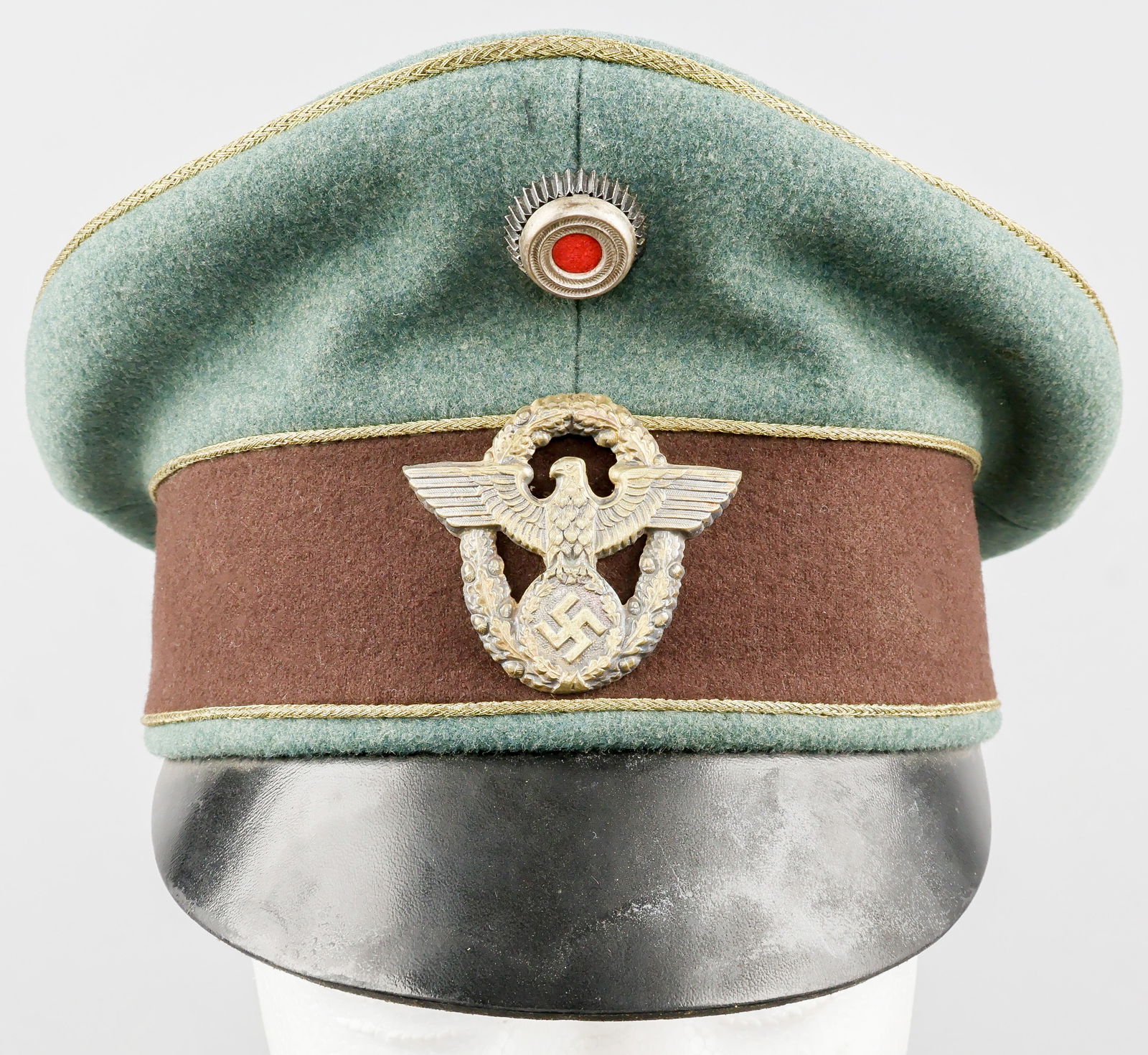 POLIZEI GENERAL OFFICER’S VISOR CAP: A Third Reich-era Polizei general officer’s visor cap, constructed of greenish-gray ‘feldgrau’ wool with a brown wool band and a black faux-leather bill. The crown and the edges of