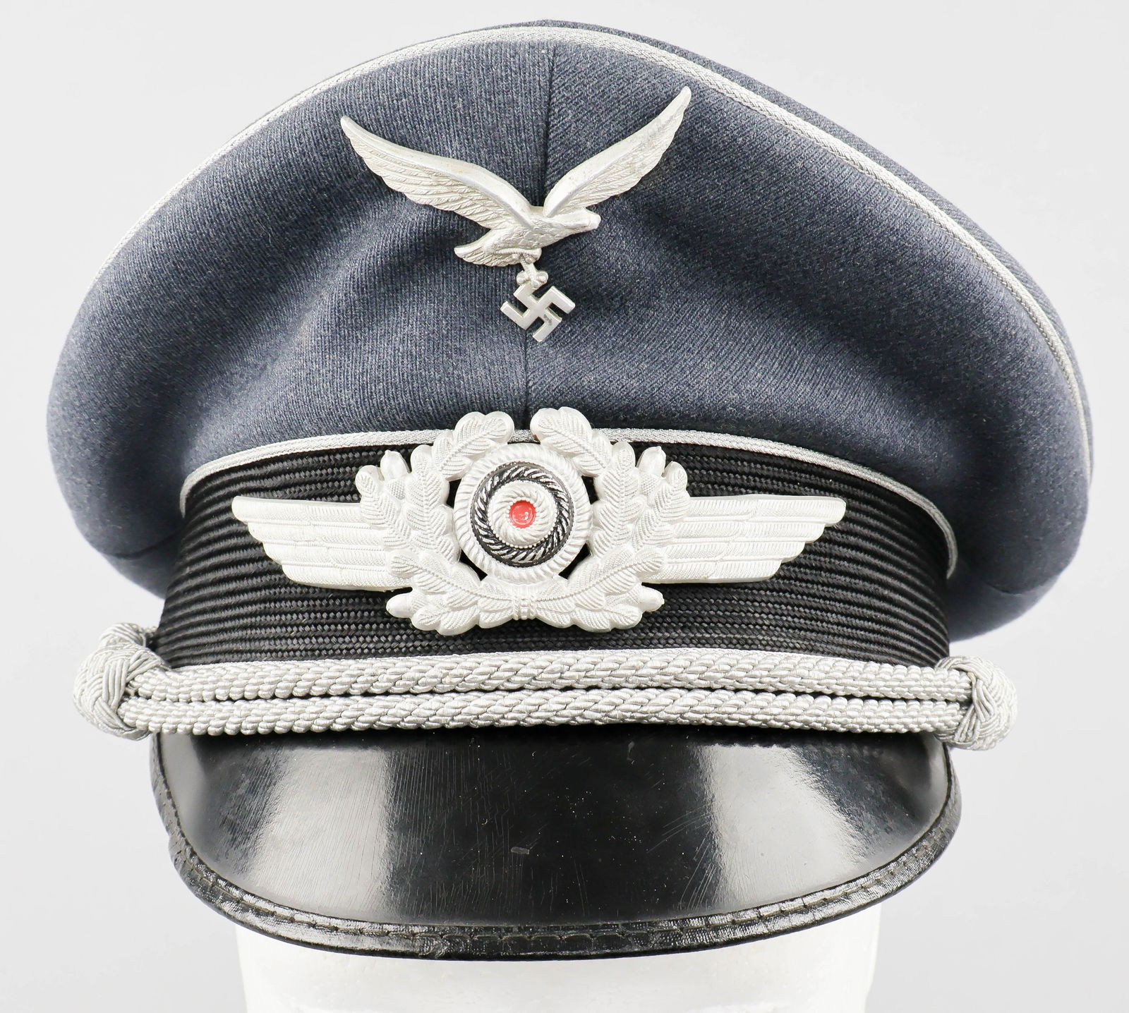 POST-WAR MANUFACTURED LUFTWAFFE OFFICER’S VISOR CAP: A well-made post-war manufactured Luftwaffe officer’s visor cap constructed of a blue-grey wool and rayon blend with a tight diagonally-ribbed texture, over a band of woven black, ribbed mohair,