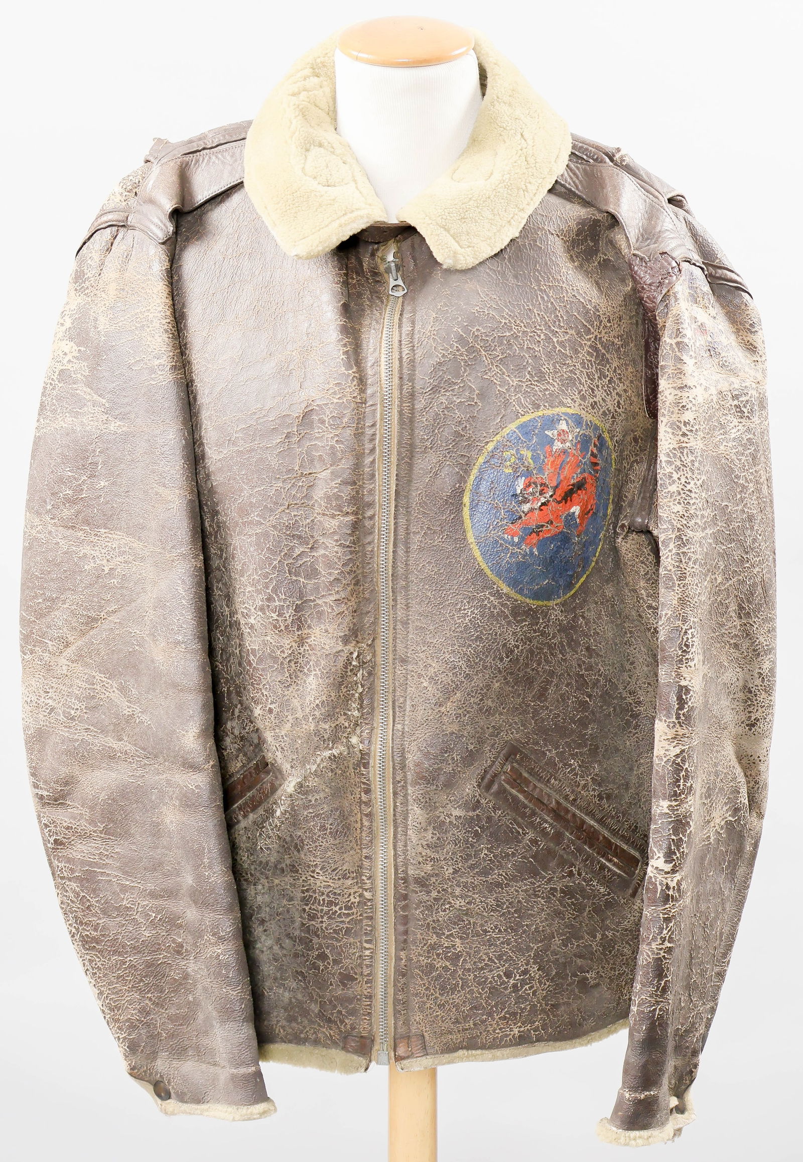 FLYING TIGERS INSIGNIA B-3 FLIGHT JACKET: Very desirable B-3 sheepskin flight jacket bearing the painted insignia of the 23rd Squadron, Flying Tigers on the left breast. The well-used jacket, size 46R, was made by the Aero Leather Clothing