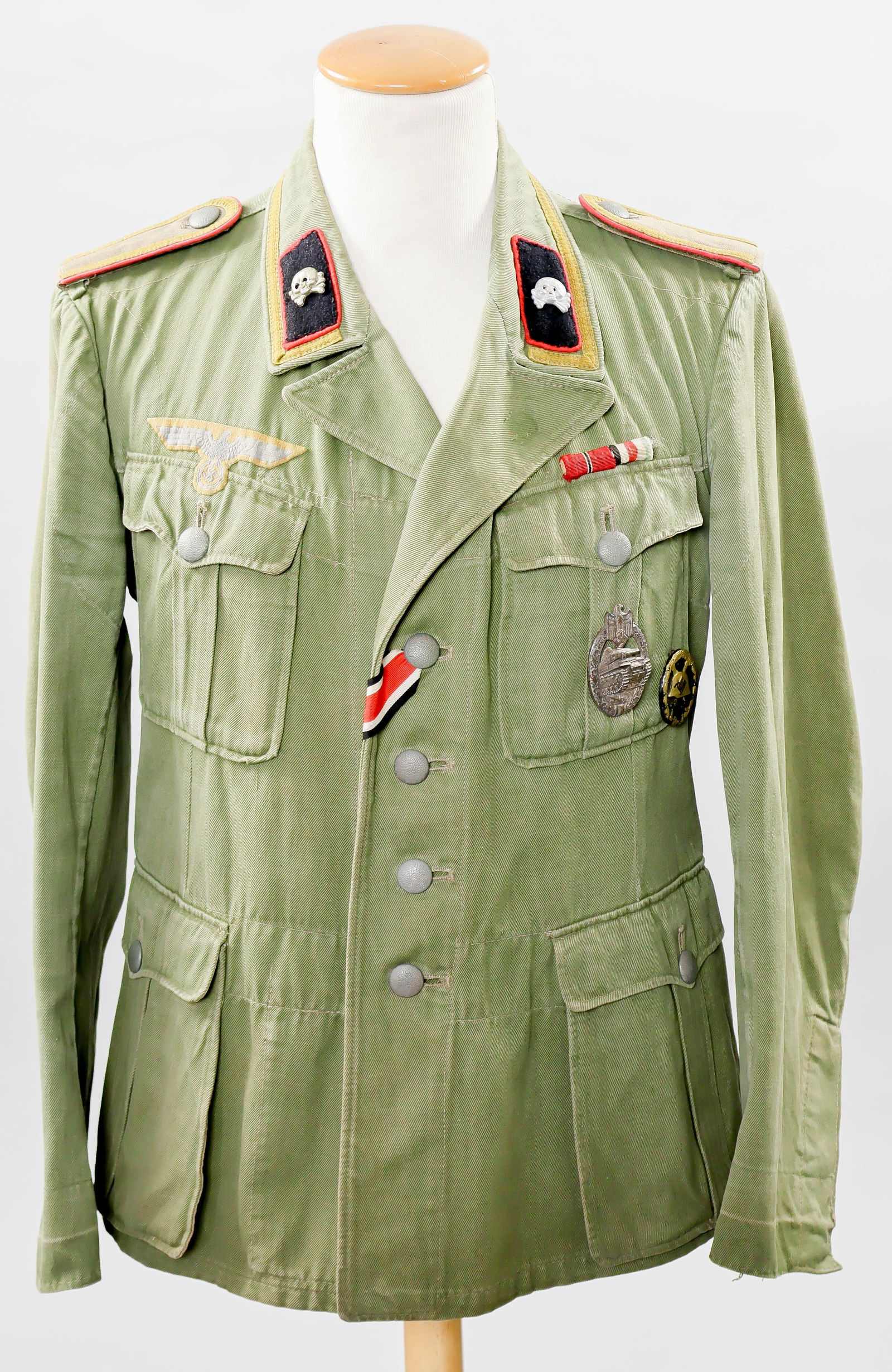 AFRIKA KORPS PANZER TROOPS NON-COMMISSIONED OFFICER’S M40 TUNIC: A very fine, first-pattern Wehrmacht tropical M40 tunic or field blouse, constructed of olive-green cotton drill, closed at the front with pebbled five metal buttons, each marked ‘H W’ on