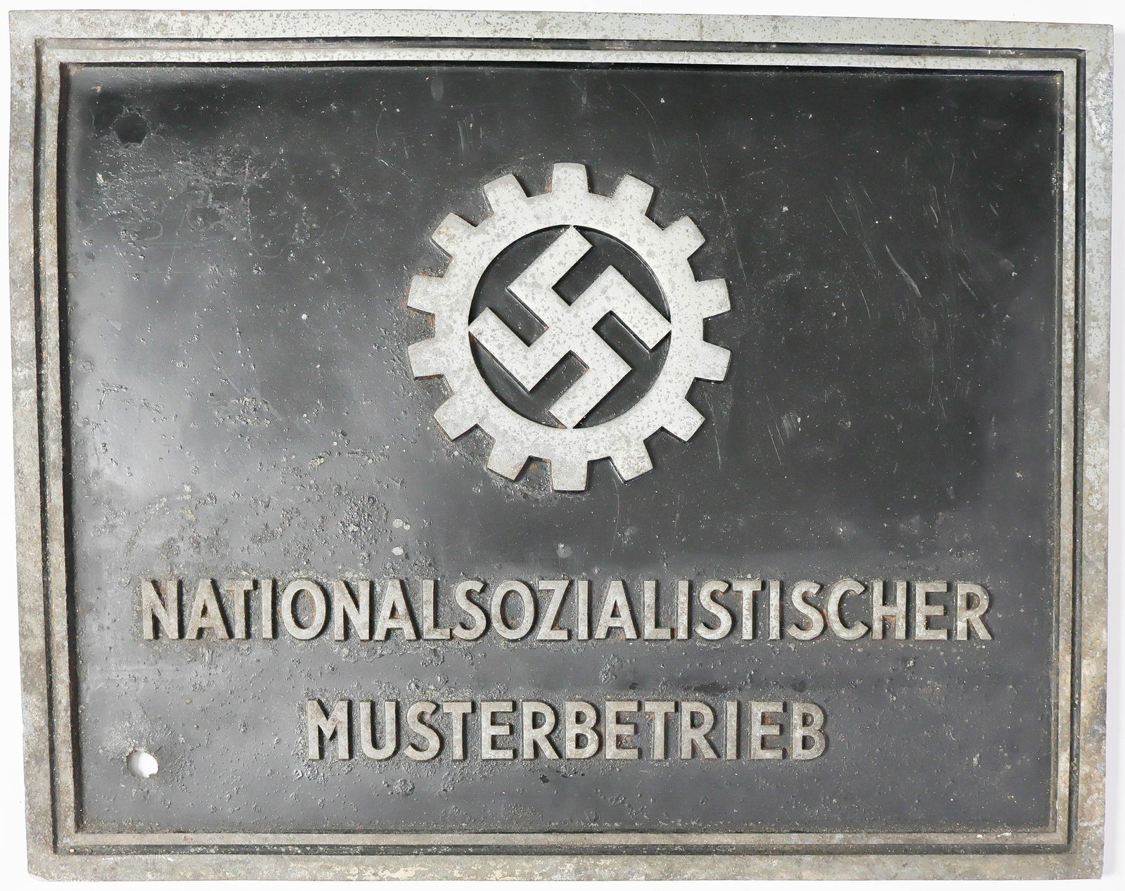 D.A.F. NATIONALSOZIALISTISCHER MUSTERBETRIEB IRON PLACARD: Rarely seen D.A.F.-issue 'NATIONALSOZIALISTISCHER MUSTERBETRIEB' iron sign, 19 x 15 in. overall, the letters in relief and set above a black background with simple linear border. The reverse of the