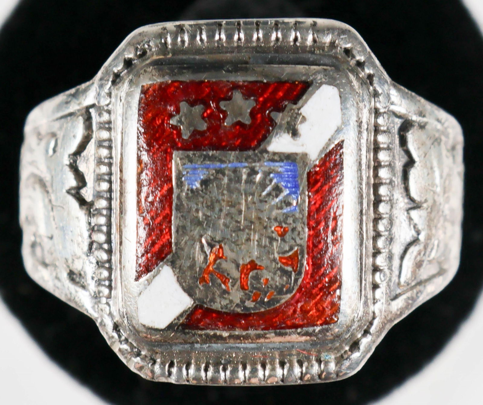 SS VOLUNTEER'S SILVER RING: Silver ring purported to have been owned by an SS volunteer, a fairly well made piece with a heraldic enameled emblem on its face with a beaded edge and well-worn filigree designs on either side. The