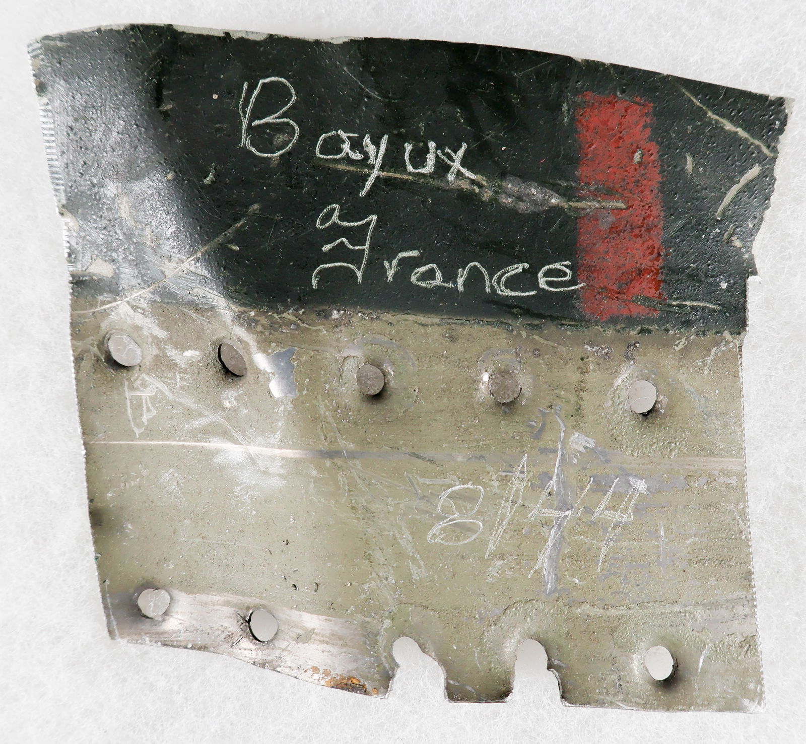SECTION OF FUSELAGE FROM A NORMANDY CRASHED GERMAN AIRCRAFT: Small section of painted aluminum fuselage from a German aircraft which crashed in Normandy, France. The 3.5 x 3 in. relic is painted in green and black and bears multiple rivet holes. It bears a