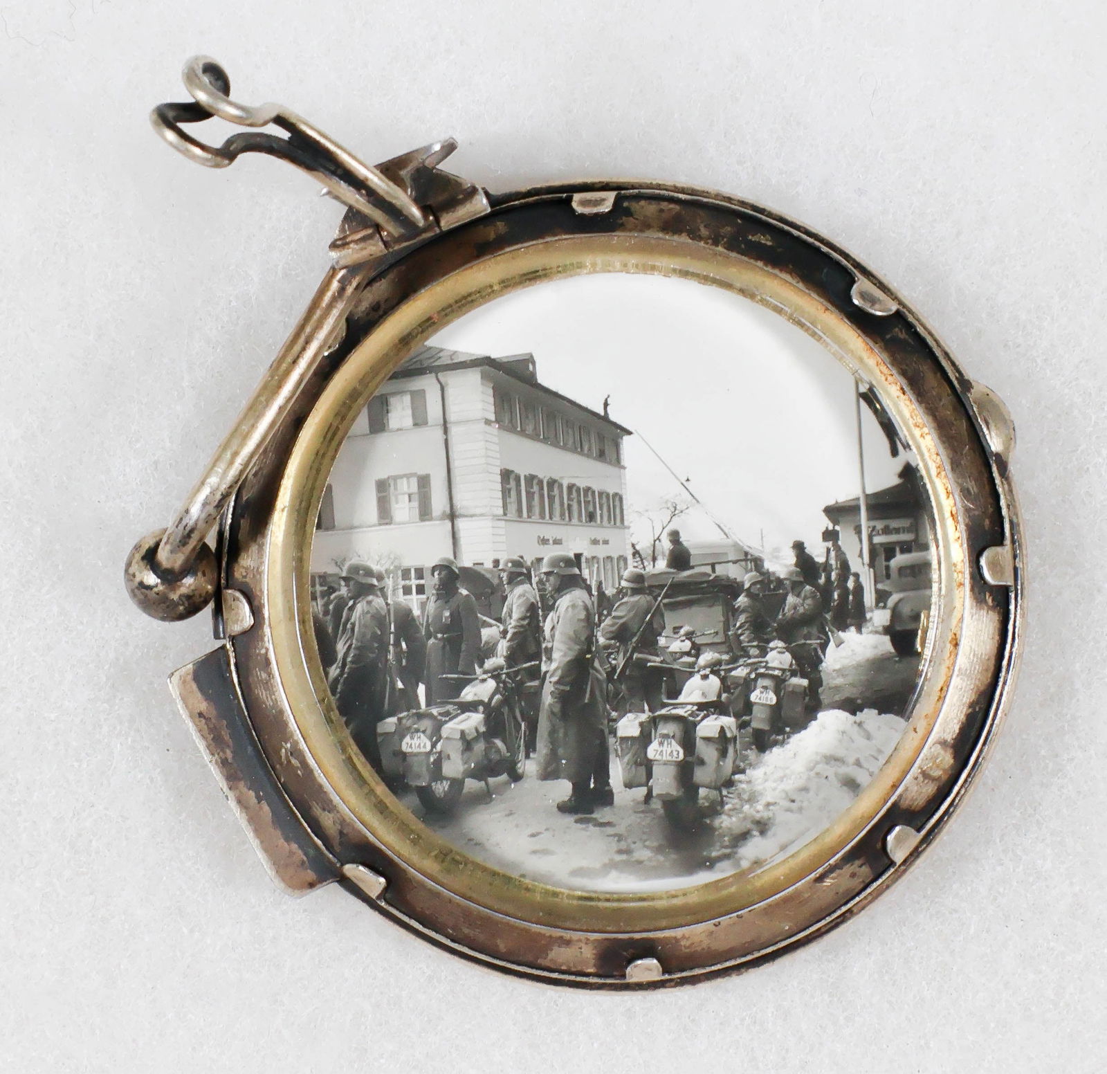 GERMAN SOLDIER'S PICTURE FRAME: An odd item, a heavily-constructed two-sided brass picture frame with brass attachment at top, about 2.25 in. wide, one side enclosing an image of SS and Heer men saluting a Mercedes which very