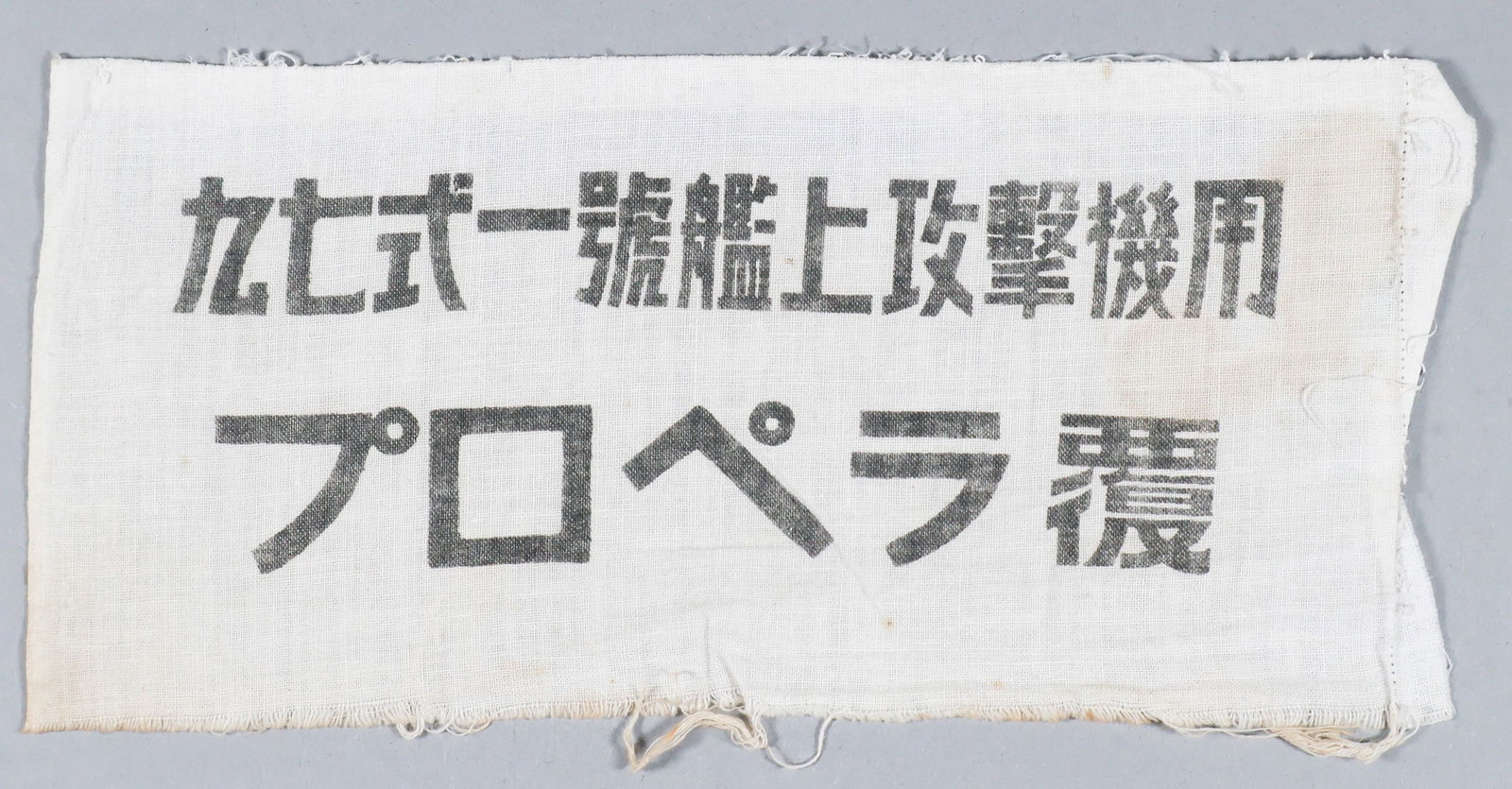 NAKAJIMA B5N 'KATE' TORPEDO BOMBER PROPELLER COVER: Small section of imprinted white cloth, 8 x 4 in., reading: 'TYPE 97 [representing the KATE] NO. 1 CARRIER-BASED ATTACK AIRCRAFT PROPELLER COVER'. Fine.