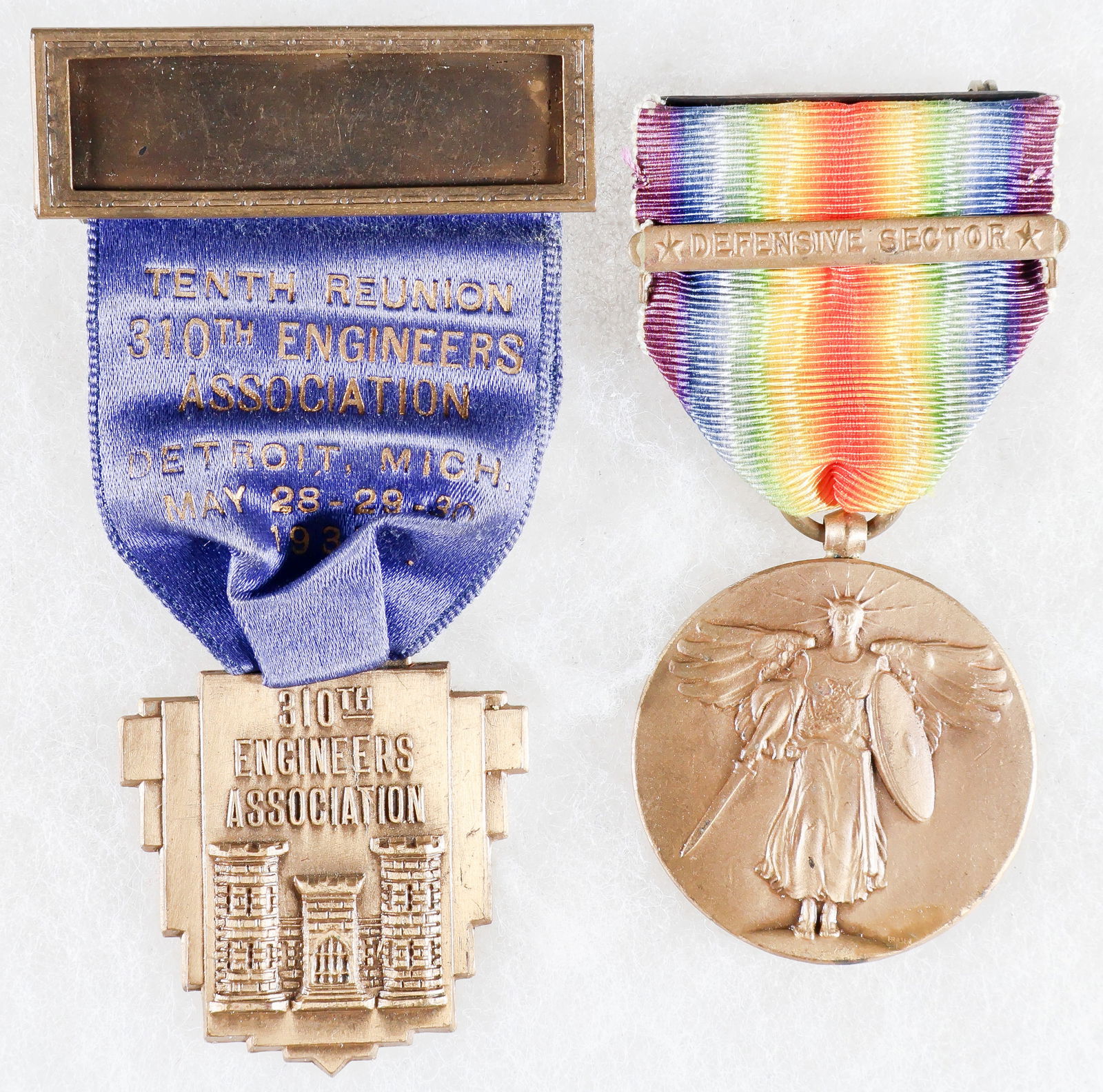 310TH ENGINEERS WORLD WAR I VICTORY MEDAL AND REUNION BADGE: A U.S. World War I Victory Medal belonging to an unidentified member of the 310th Engineers, with rainbow-patterned suspension ribbon fitted with a Defensive Sector clasp. The medal is accompanied by