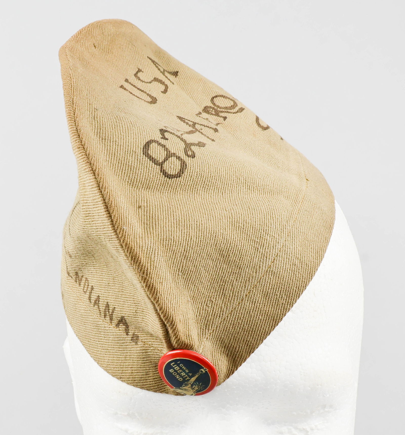 82ND AERO SQUADRON SOUVENIR CAP: A rounded, likely child-size cap of tan wool or cotton twill, inscribed on one side in black ink: ‘Fred. M. Cook. Ft. Wayne. Indiana’ over ‘82nd Aero Squadron’. The opposite si