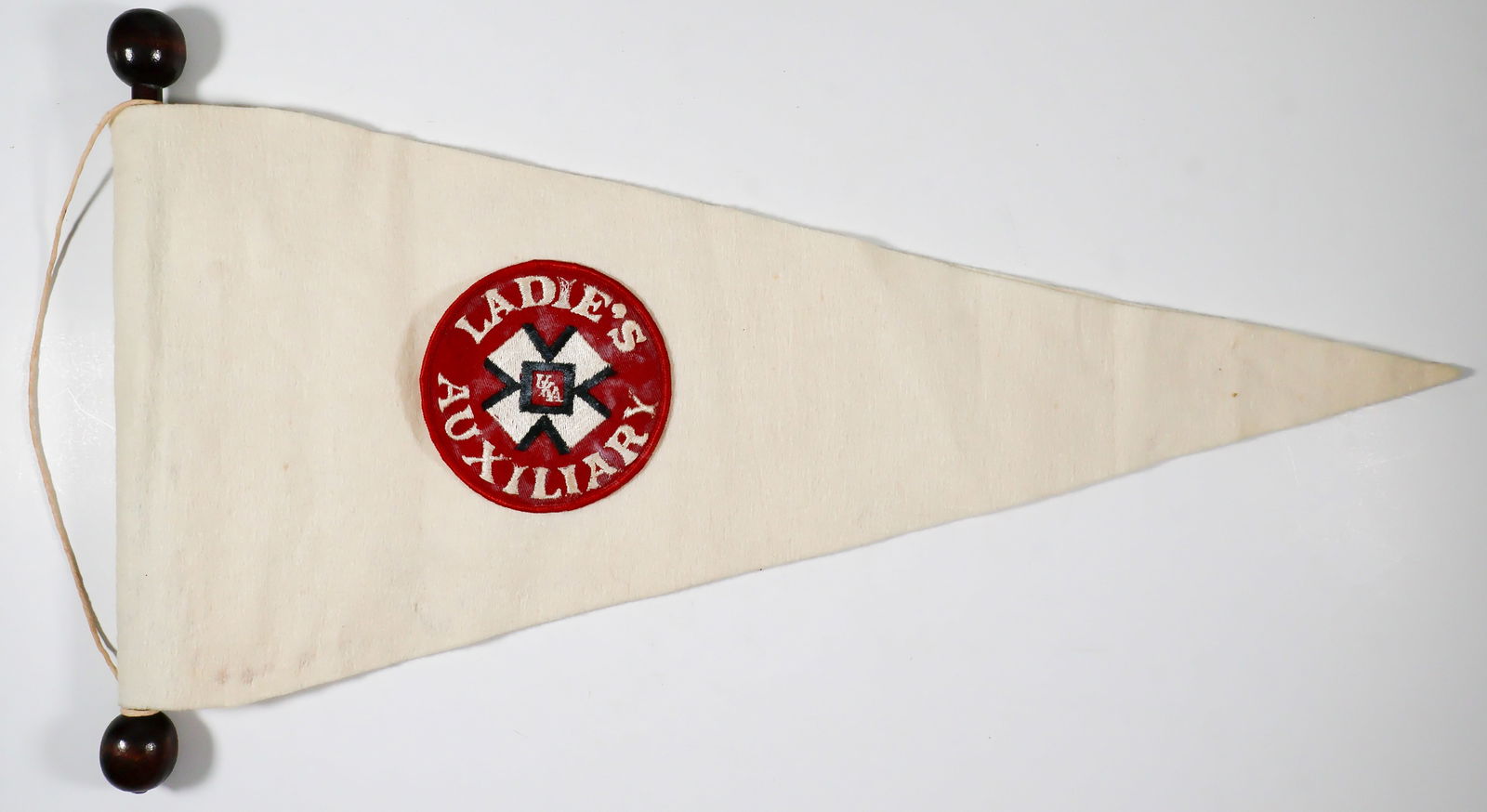 KU KLUX KLAN LADIES AUXILIARY PENNANT: A white felt pennant, 20.5 in. long x 9 in. at widest point, clearly handmade with its edges displaying glued construction, attached to a 12 in. wood pole and bearing a large ‘Ladie’s