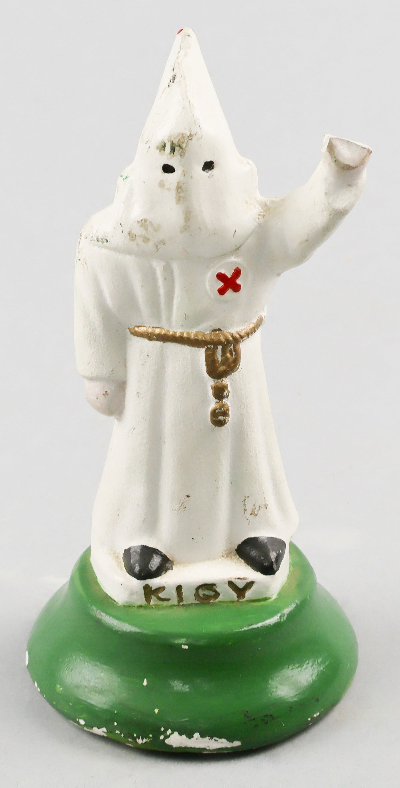 ROBED KLANSMAN STATUE: Chalkware statue of a Ku Klux Klan member fully dressed in robes and a hood with the left proper hand raised in salute, standing 5.75 in. tall atop a wooden base with a felt bottom. Engraved at the