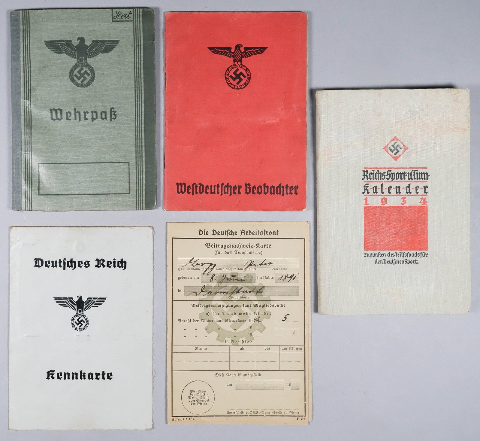 THIRD REICH DOCUMENTS (5): A group of identification booklets, includes a Wehrpass, Reichs Sports calendar for 1934, ‘Kennkarte’ (civilian identification card), and two coupon booklets. Overall good to very good.