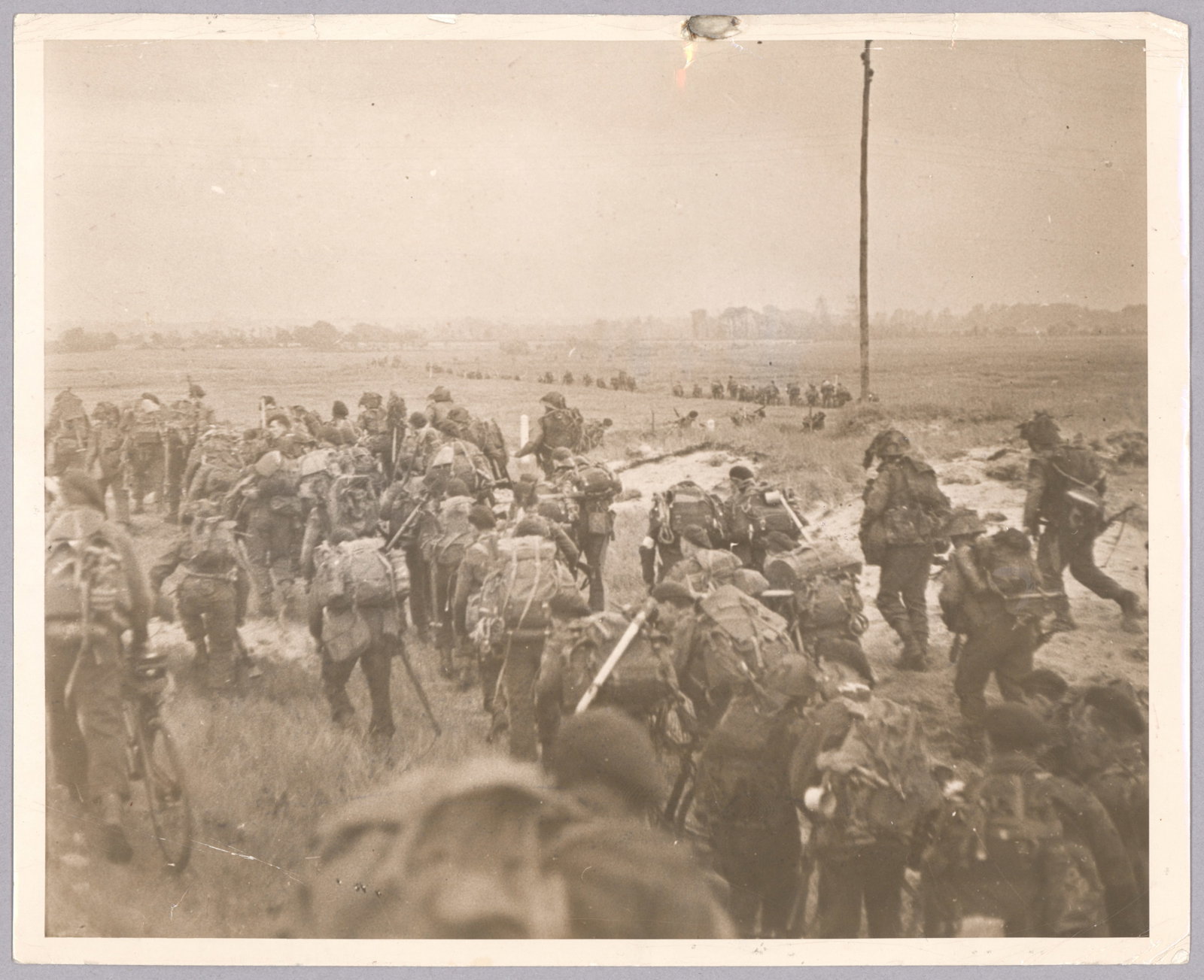 (D-DAY) BRITISH SPECIAL SERVICE TROOPS MOVE OFF THE BEACH: Rare, original period press photograph, 8 x 10 in. b/w, depicts British Special Service troops as they just clear one of the British landing beaches and move inland on D-Day, June 6, 1944. Verso