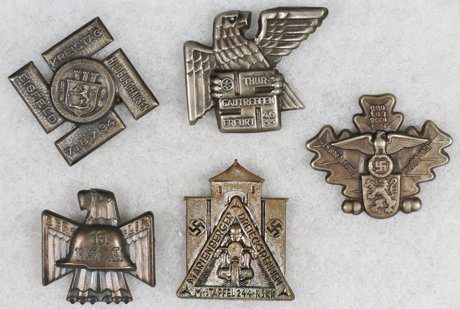 1930s GERMAN TINNIES (5): A group of five World War II tinnies, includes: a Marienberger Dreieksrenne pin indicating participation in a motorcycle ‘triangle race’ organized by the NSKK, 1930s; a tinnie from a ̵