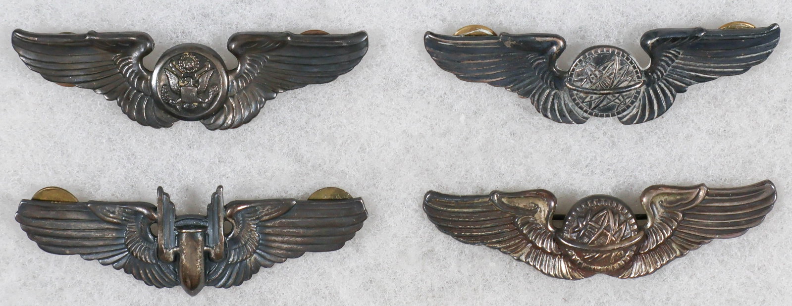ARMY AIR CORPS WINGS (4): Set of four A.A.C. wings, three clutch-back alloy including Air Crew, Navigator, and Air Gunner, with a second Navigator with pin-back and in sterling. Good condition.