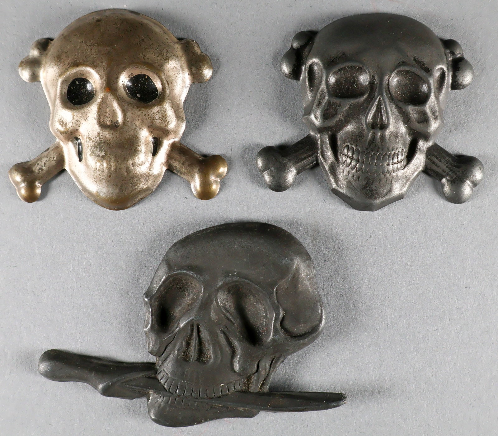 FASCIST INSIGNIA (2): Two pieces of skull insignia, blackened finish with pins on verso, each about 2 in. tall, with a third silver skull, clearly a later copy. Sold as is.