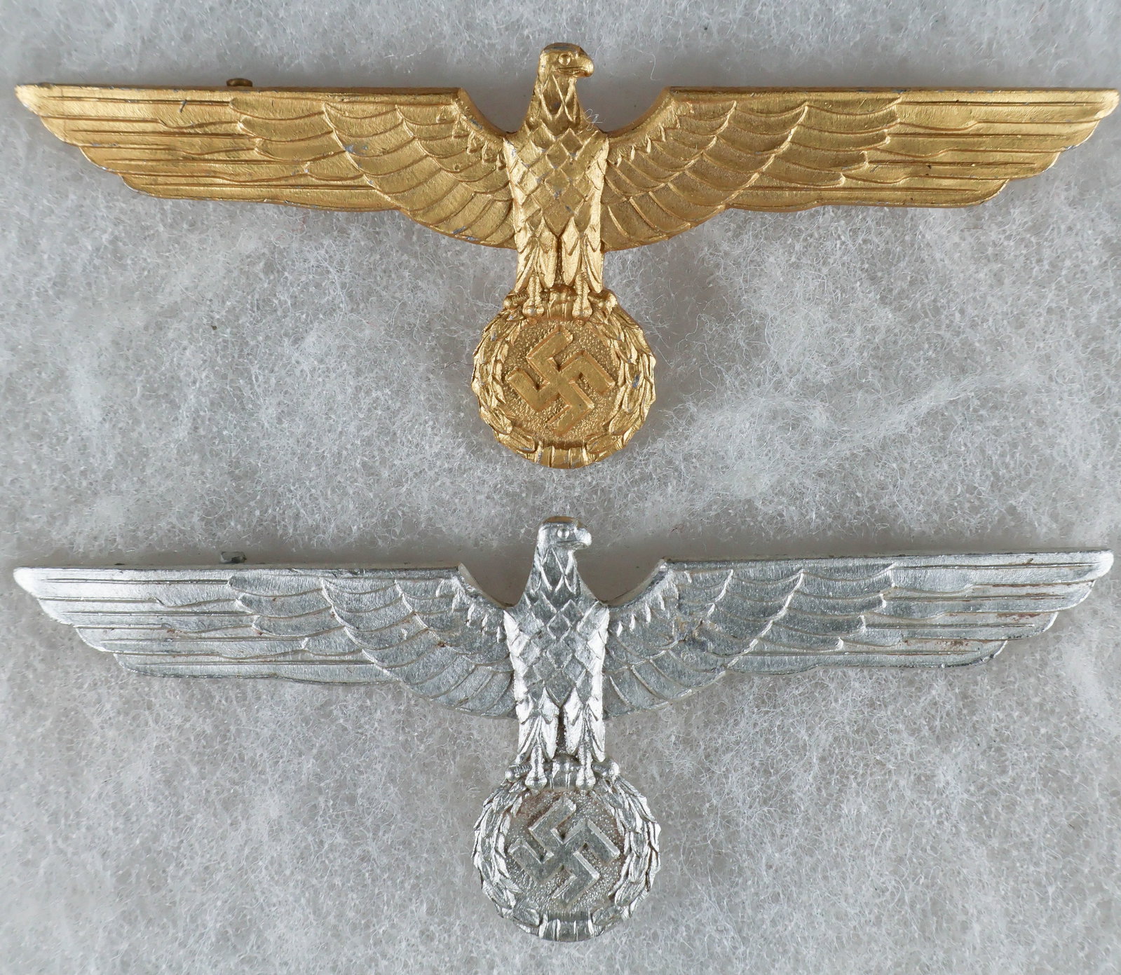 HEER AND KRIEGSMARINE OFFICERS’ SUMMER TUNIC BREAST EAGLES (2): A fine pair of Wehrmacht officers’ summer uniform breast eagle badges, each approx. 3.75 x 1.15 in., including the silver-colored aluminum version worn by Heer officers, and the gold version