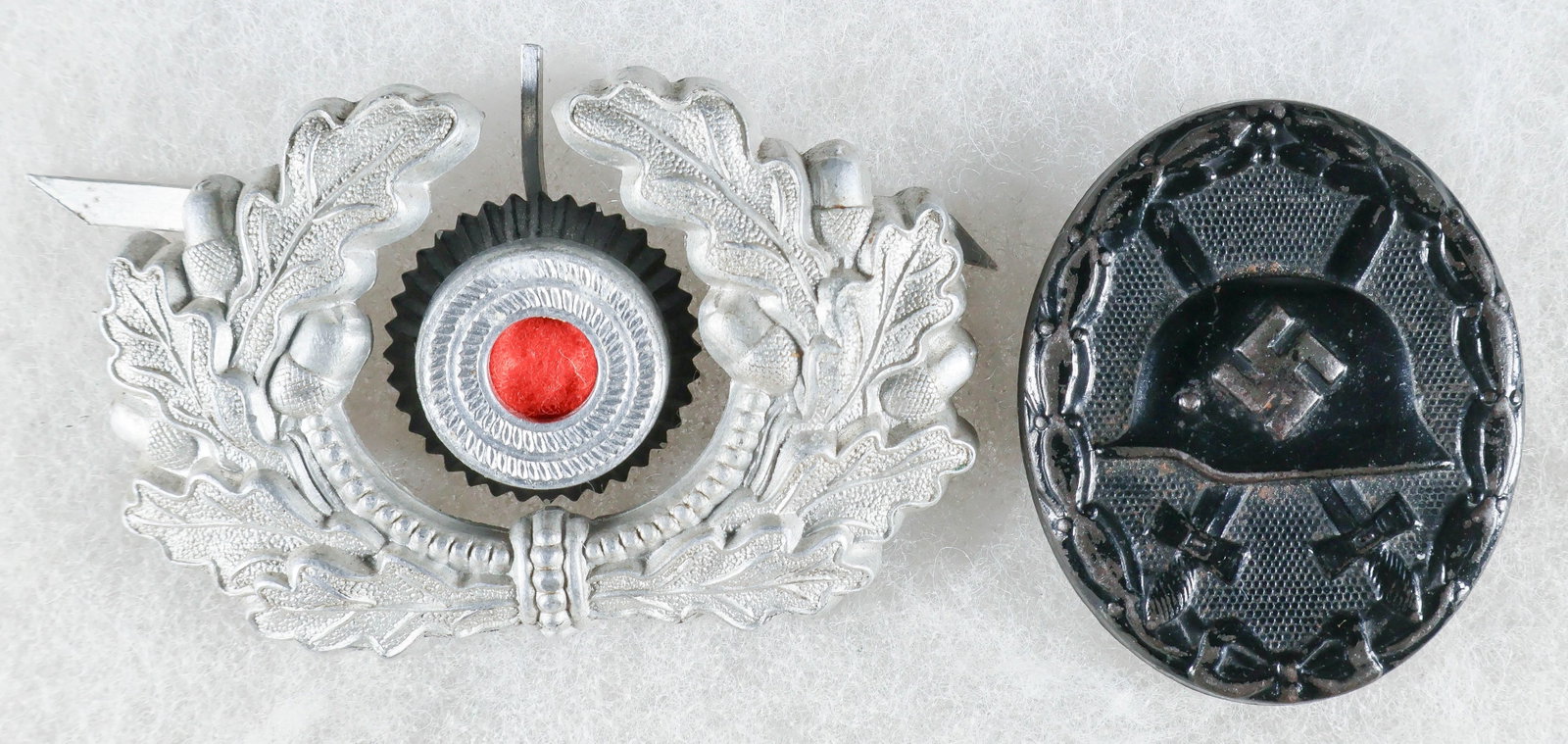 HEER OFFICER’S CAP WREATH AND COCKADE, WOUND BADGE IN BLACK: A Heer officer’s visor cap wreath of stamped zinc, with three pin attachments on the reverse, unmarked, with a stamped zinc cockade with red wool center, marked ‘H. V.’ over