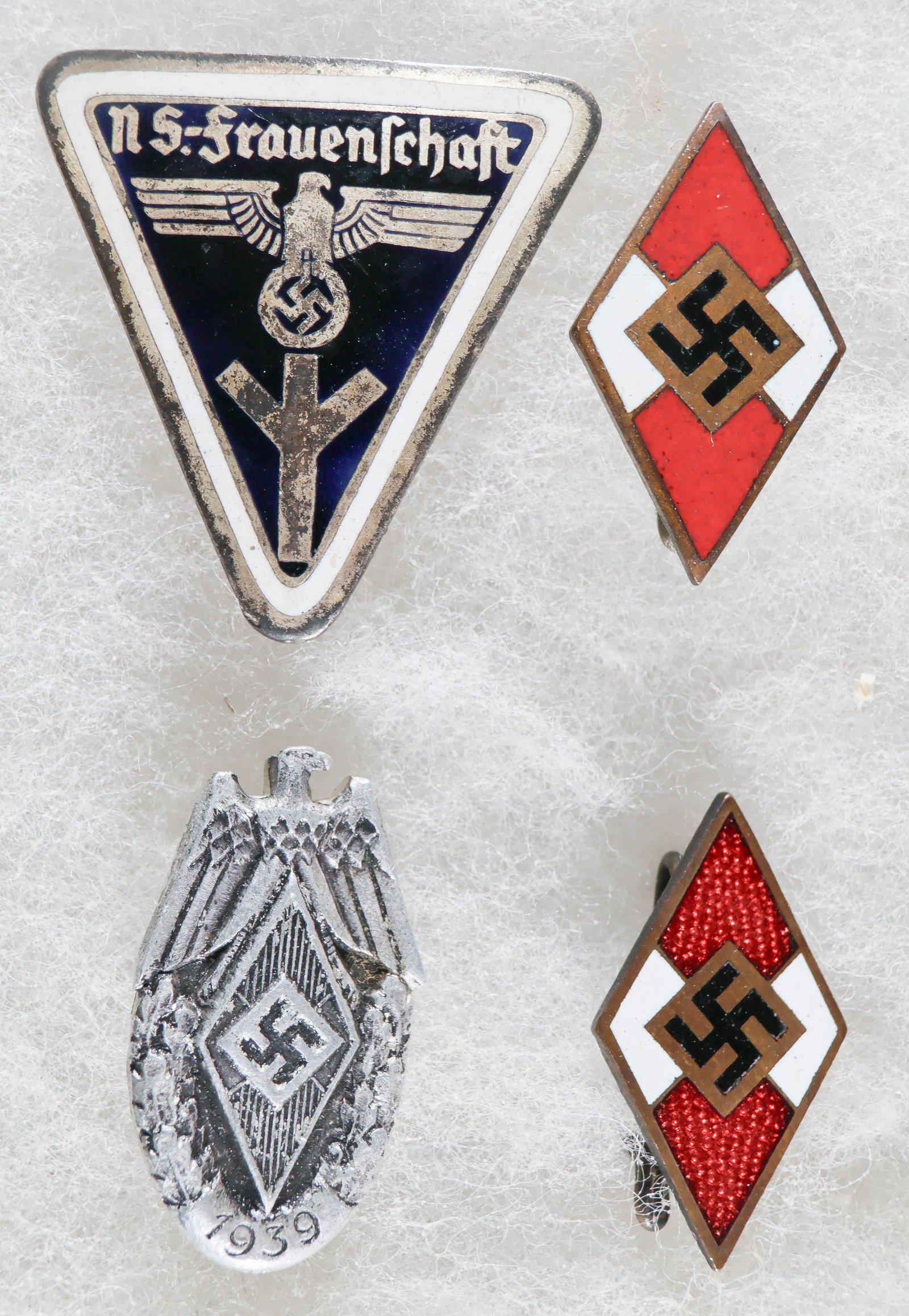 HITLER YOUTH AND N. S.-FRAUENSCHAFT BADGES (4): Good lot of four Third Reich badges, includes two enameled metal Hitler Youth membership badges, both with pinback clasps and both RZM-marked, the first ‘M1/72’ and the second