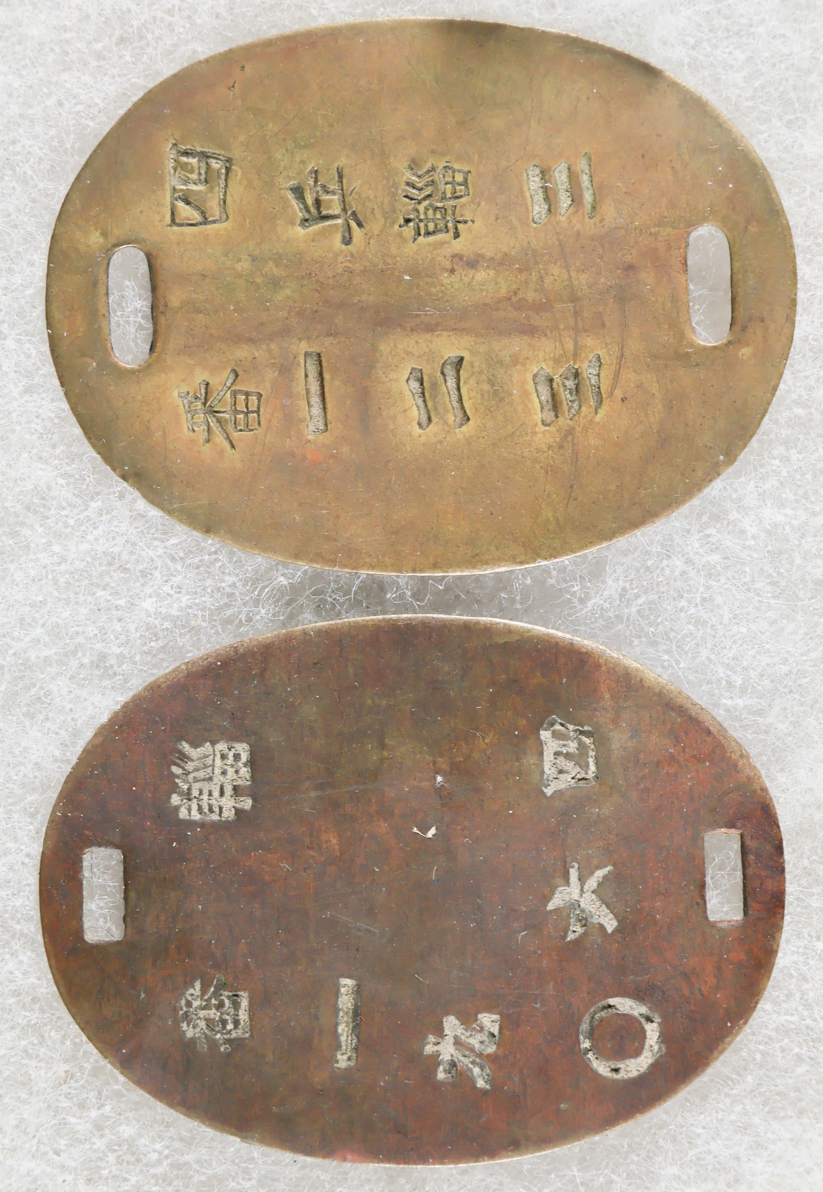 IMPERIAL JAPANESE ARMY SOLDIER’S IDENTIFICATION TAGS (2): Good pair of brass Imperial Japanese Army identification tags or dog tags, each 1.25 x 1.75 in., the first stamped with two vertical rows of kanji identifying the owner’s unit, the 3rd Supply