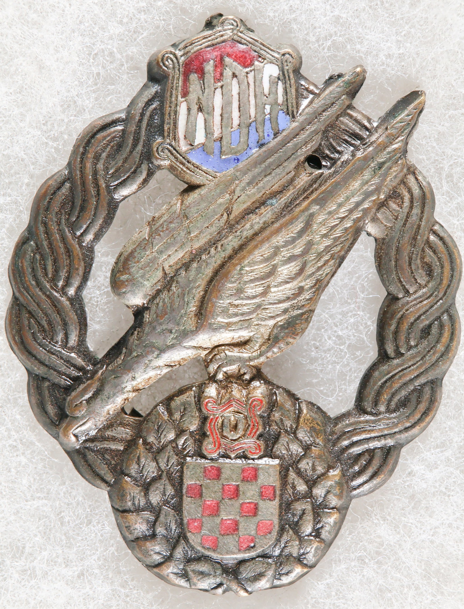 INDEPENDENT STATE OF CROATIA AIR FORCE PARACHUTIST’S BADGE: A rare World War II-era stamped zinc badge, 1.5 x 2 in., awarded to qualified parachutists of the ‘Zrakoplovstvo Nezavisne Drzave Hrvatske' (ZNDH) the air force of the Independent State of